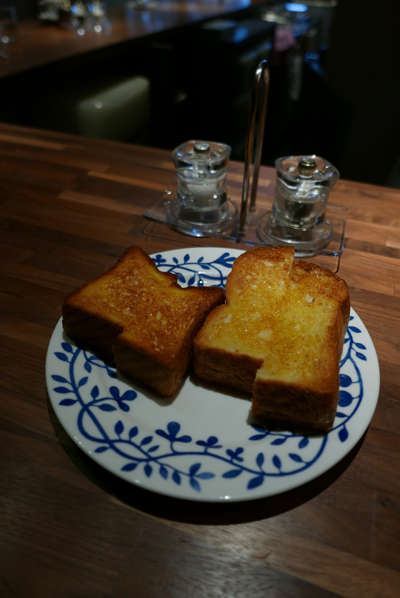 Rebanadas de pan tostado en un plato decorativo con salero y pimentero