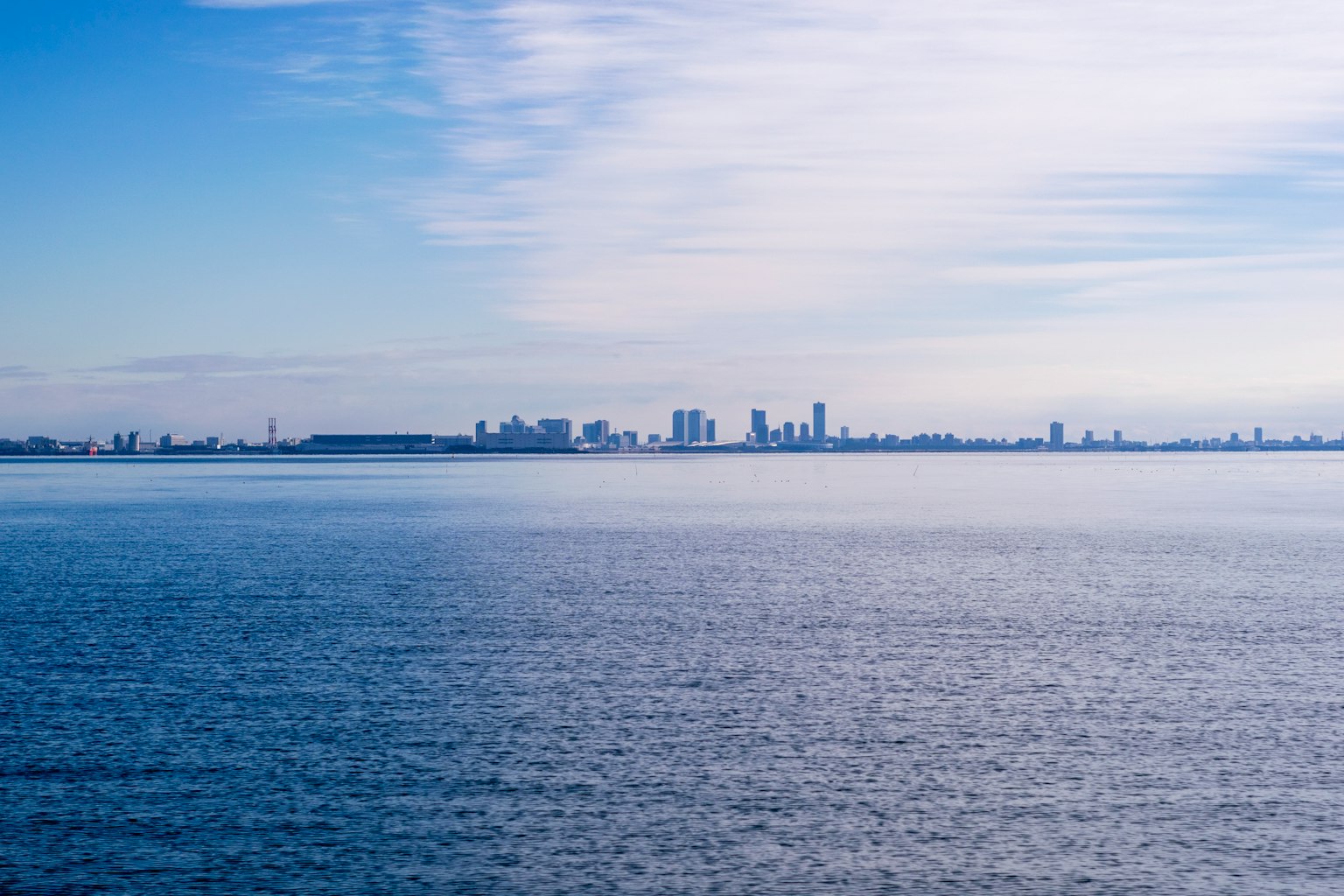 Skyline di una città contro un mare blu e un cielo luminoso