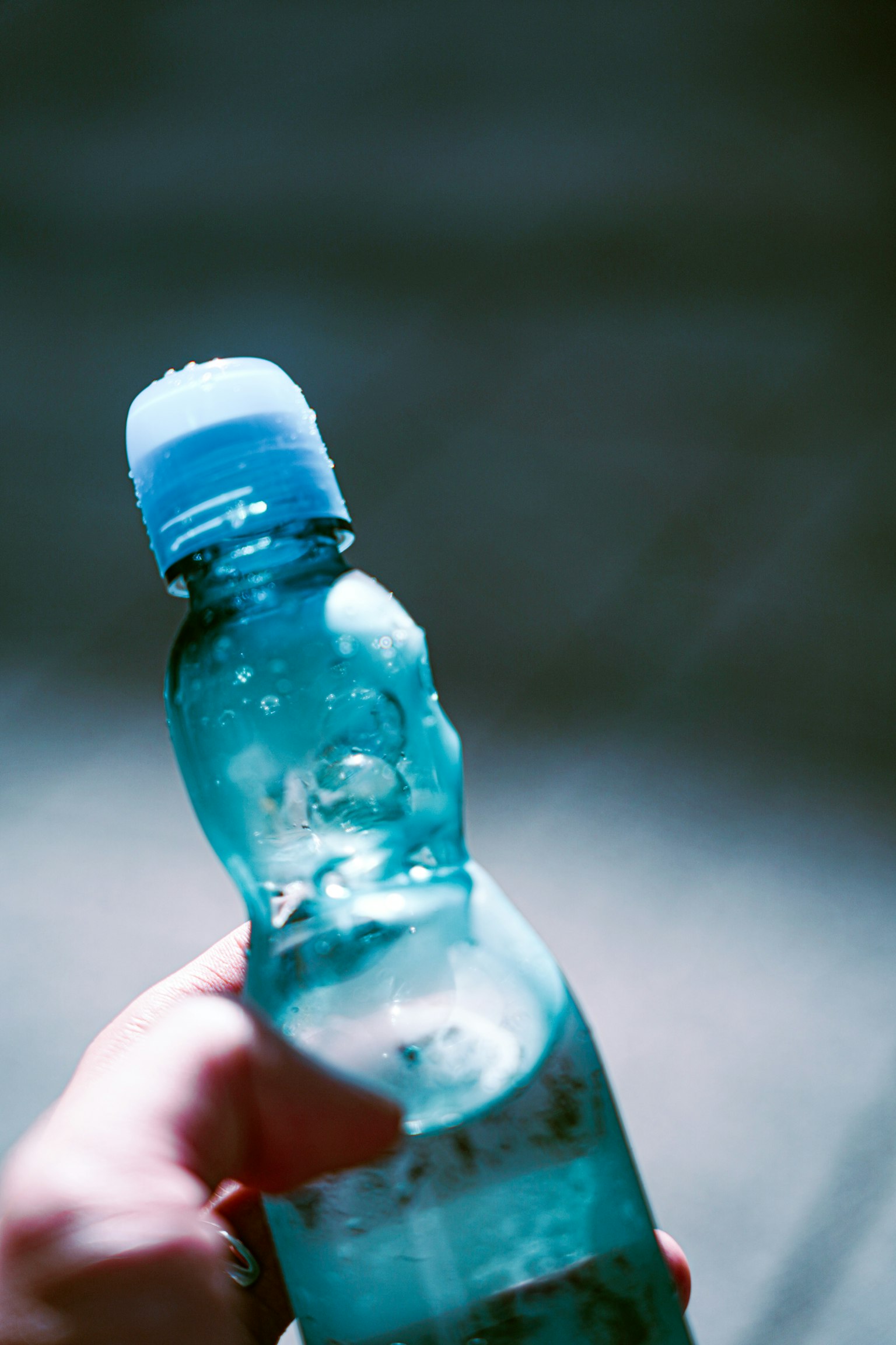 Nahaufnahme einer Hand, die eine blaue Wasserflasche hält