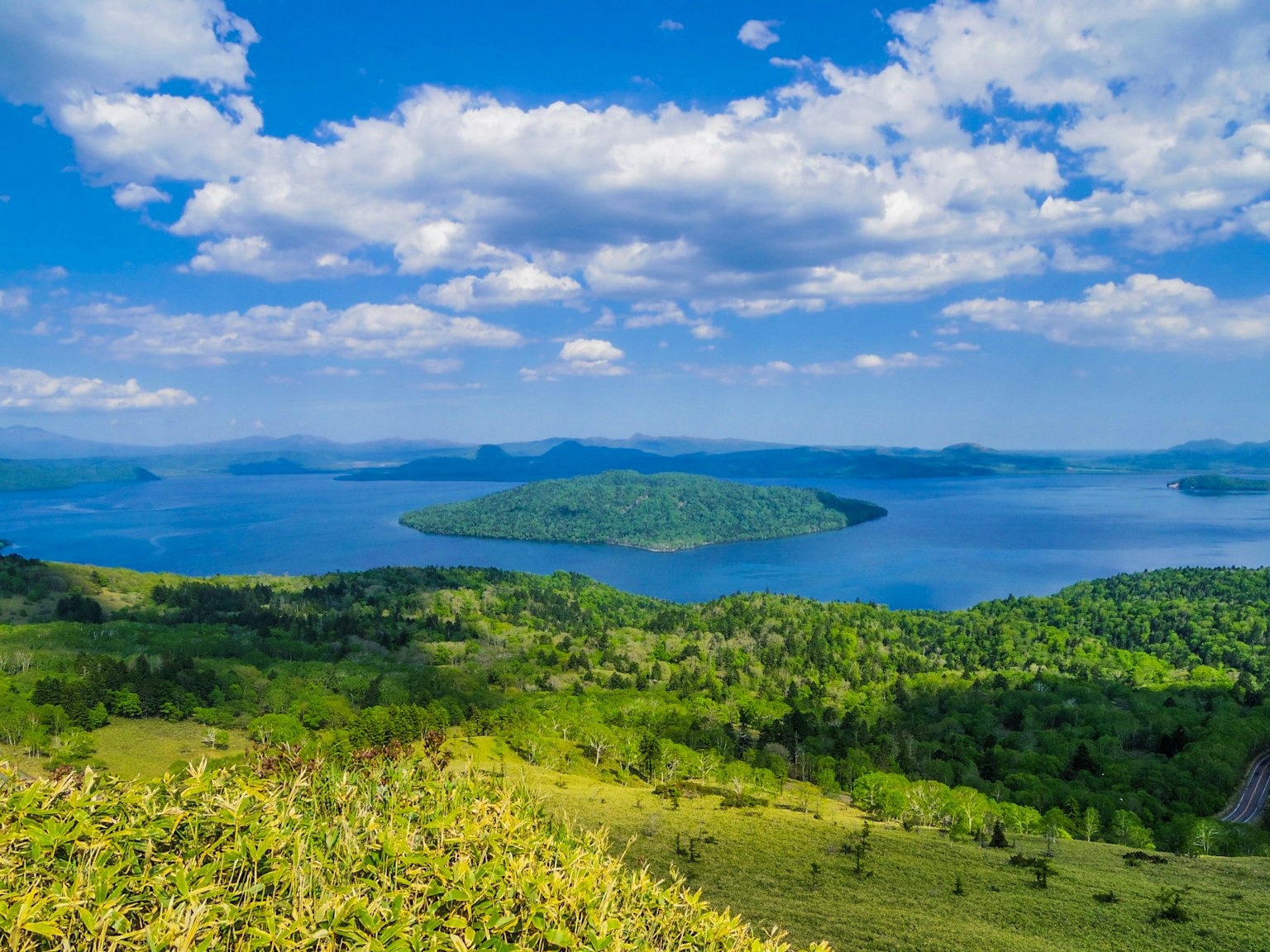 Vista panoramica di un lago blu circondato da colline verdi e isole