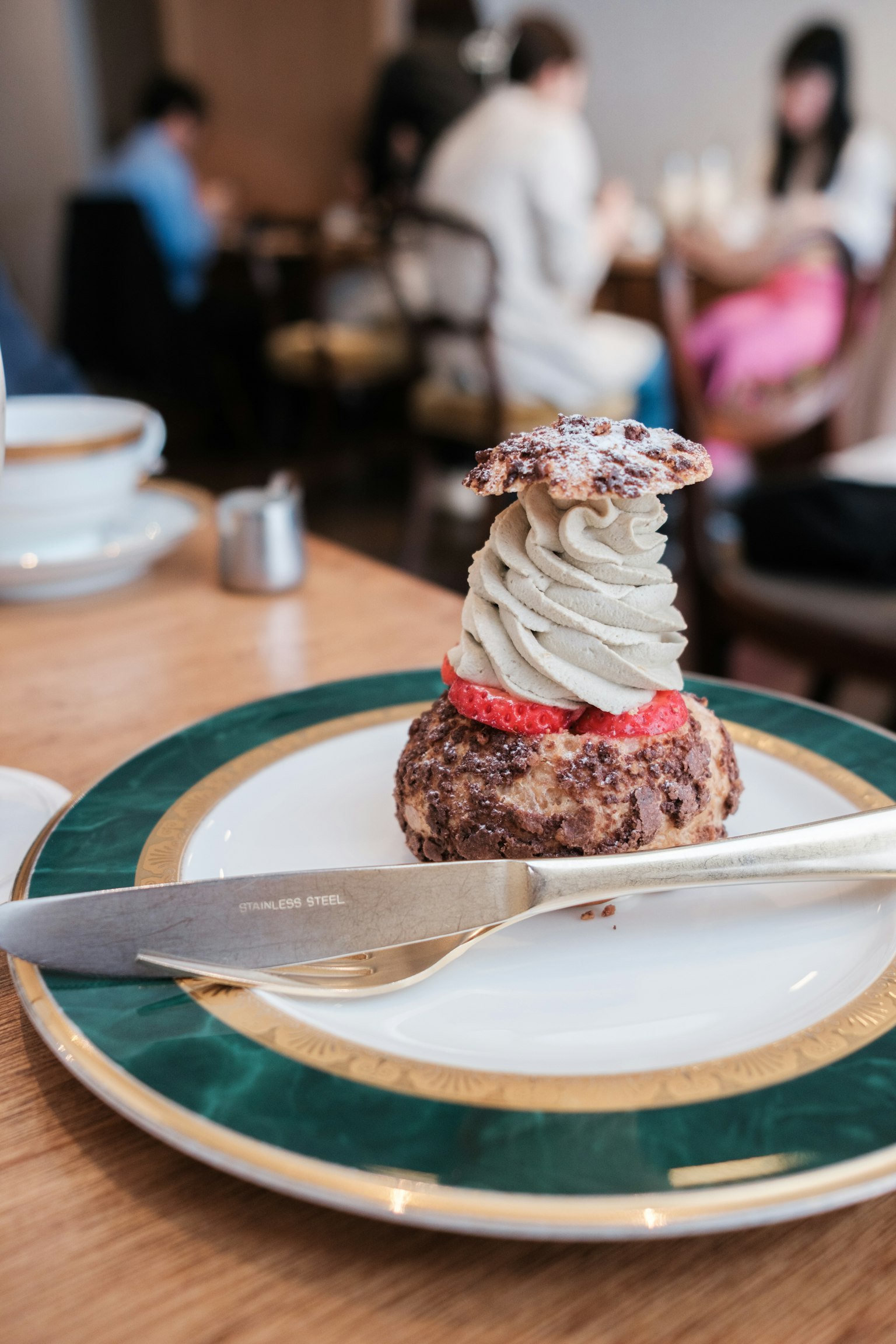 Meja kafe bergaya dengan piring dessert yang dihiasi krim dan buah