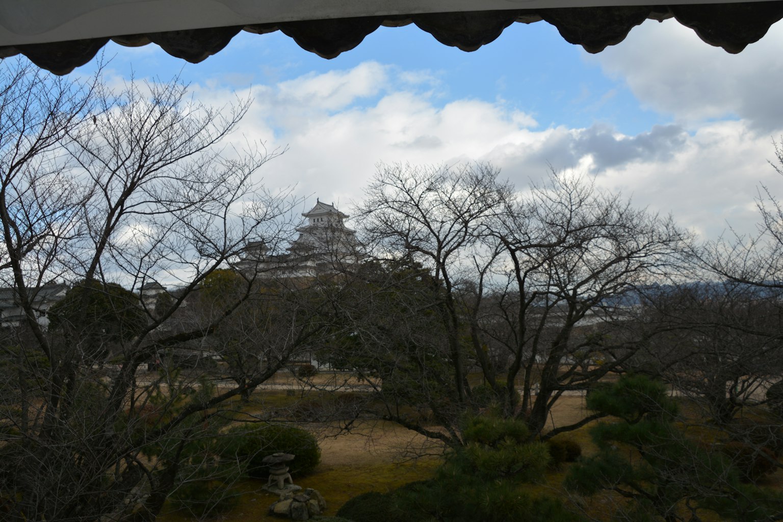 Vista lontana del castello di Himeji incorniciato da alberi spogli