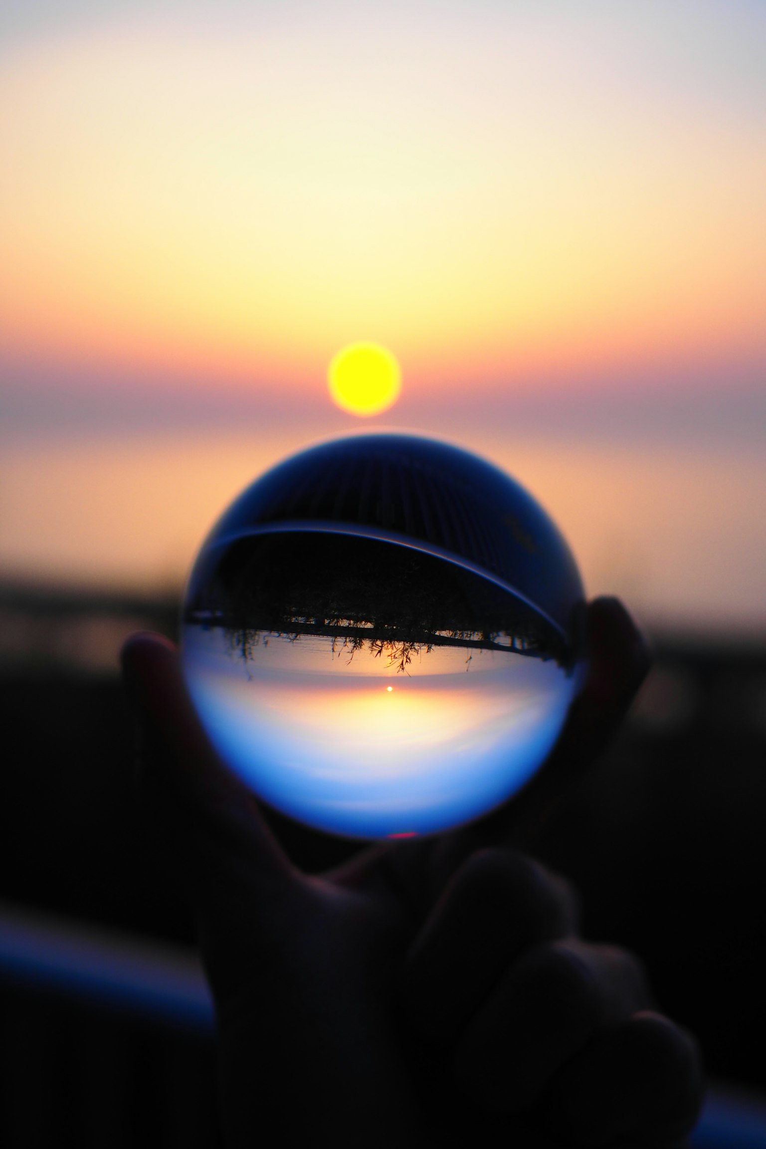 Eine Glaskugel, die einen Sonnenuntergang über dem Ozean spiegelt