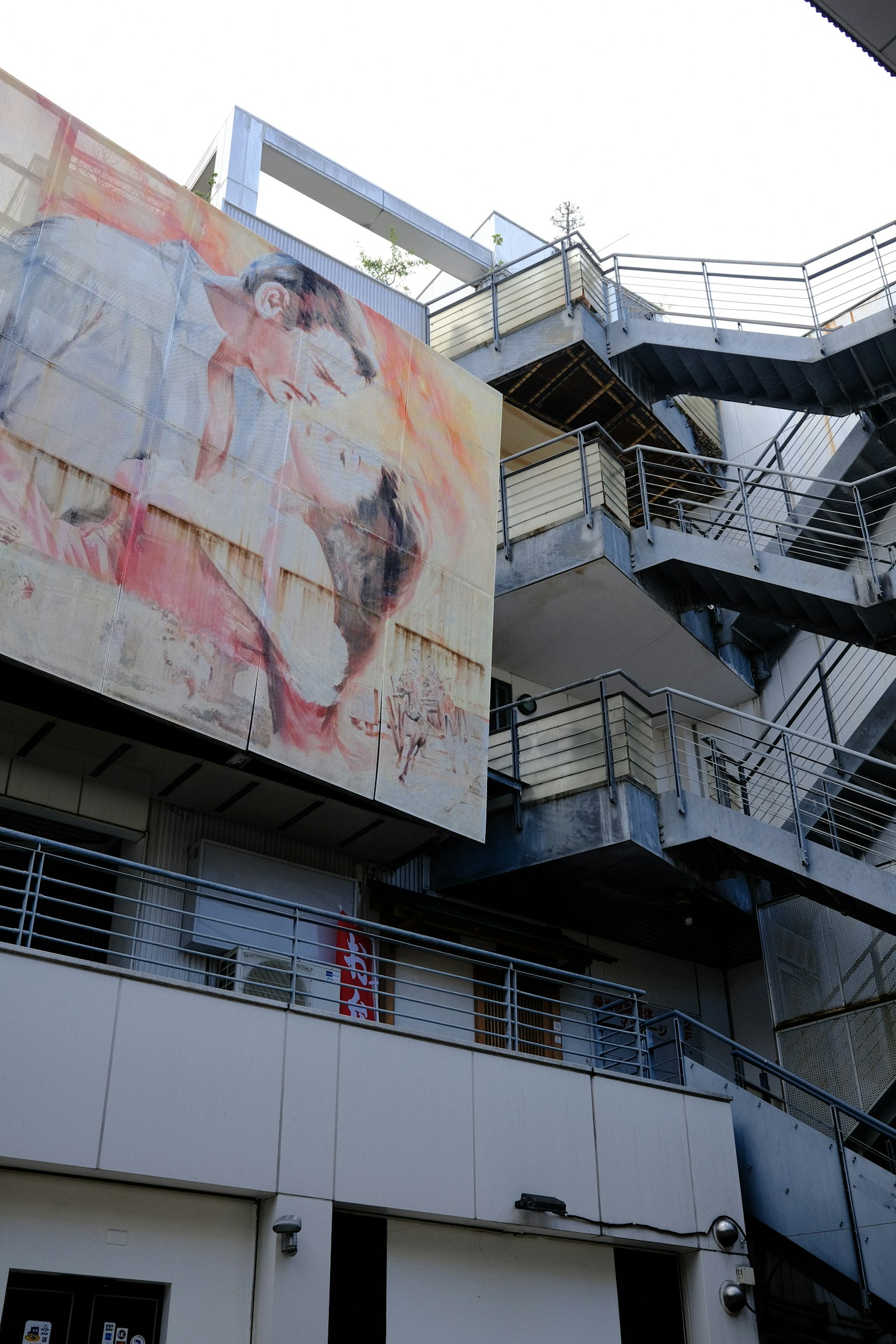 Un grande murale sull'esterno di un edificio con scale metalliche visibili