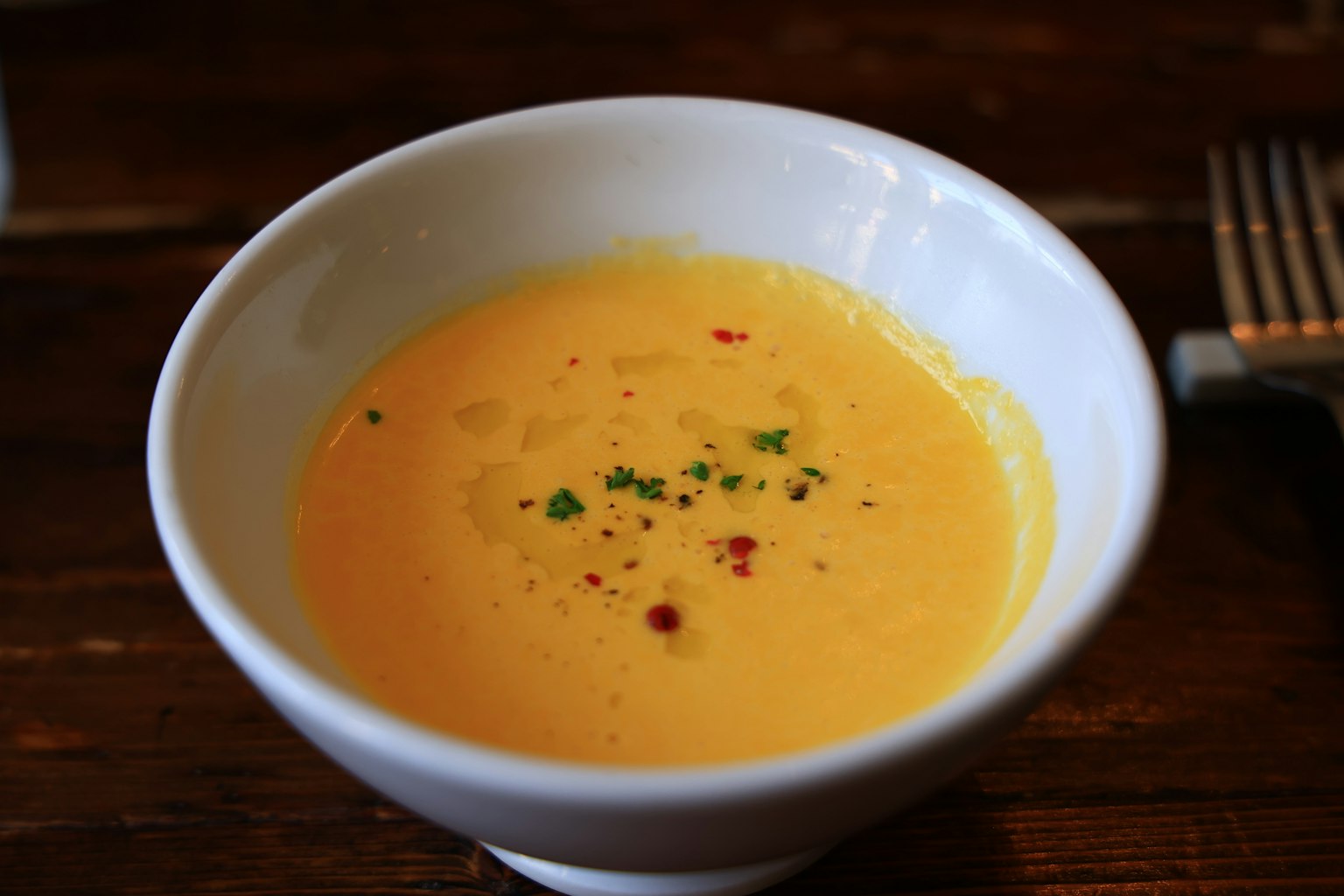 Soupe jaune crémeuse servie dans un bol blanc