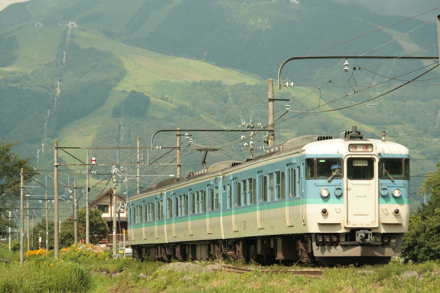 Blue train running against a mountainous backdrop
