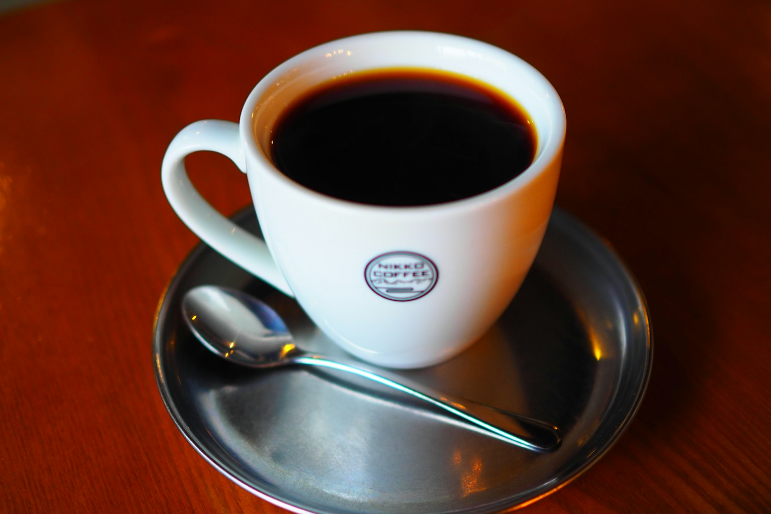 Une tasse de café blanche remplie de café noir et une cuillère