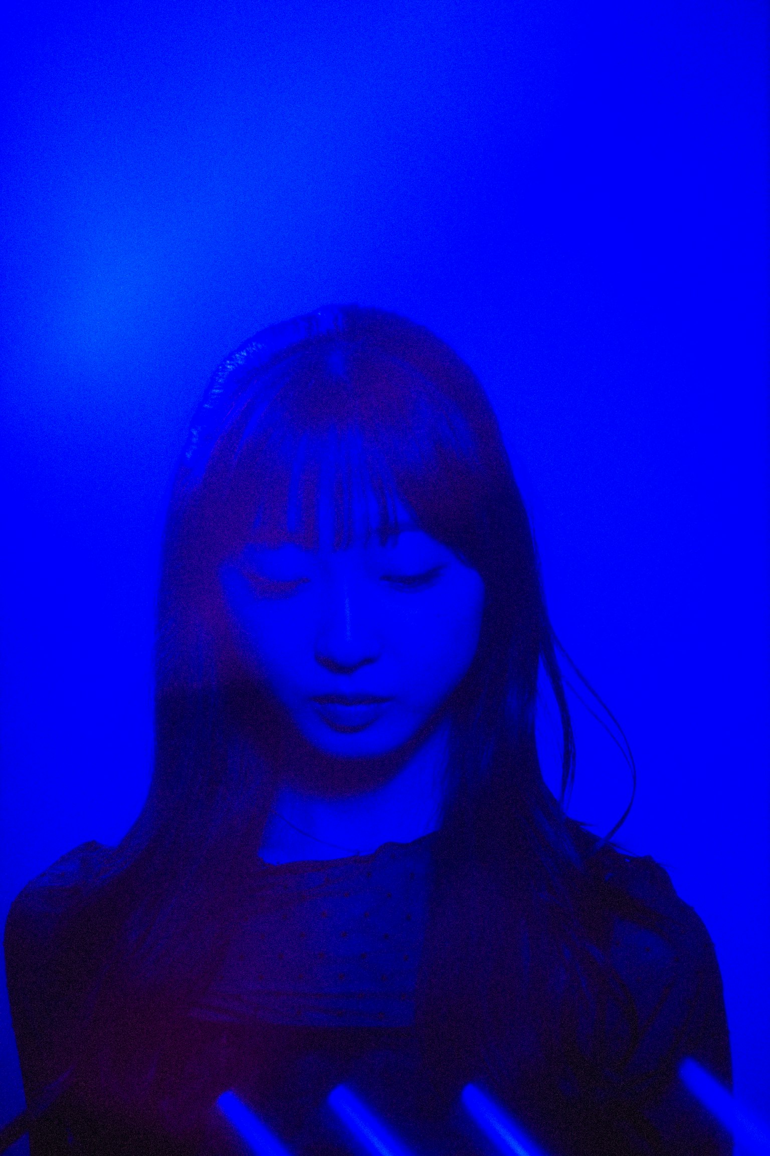 Silhouette d'une femme regardant vers le bas dans une lumière bleue