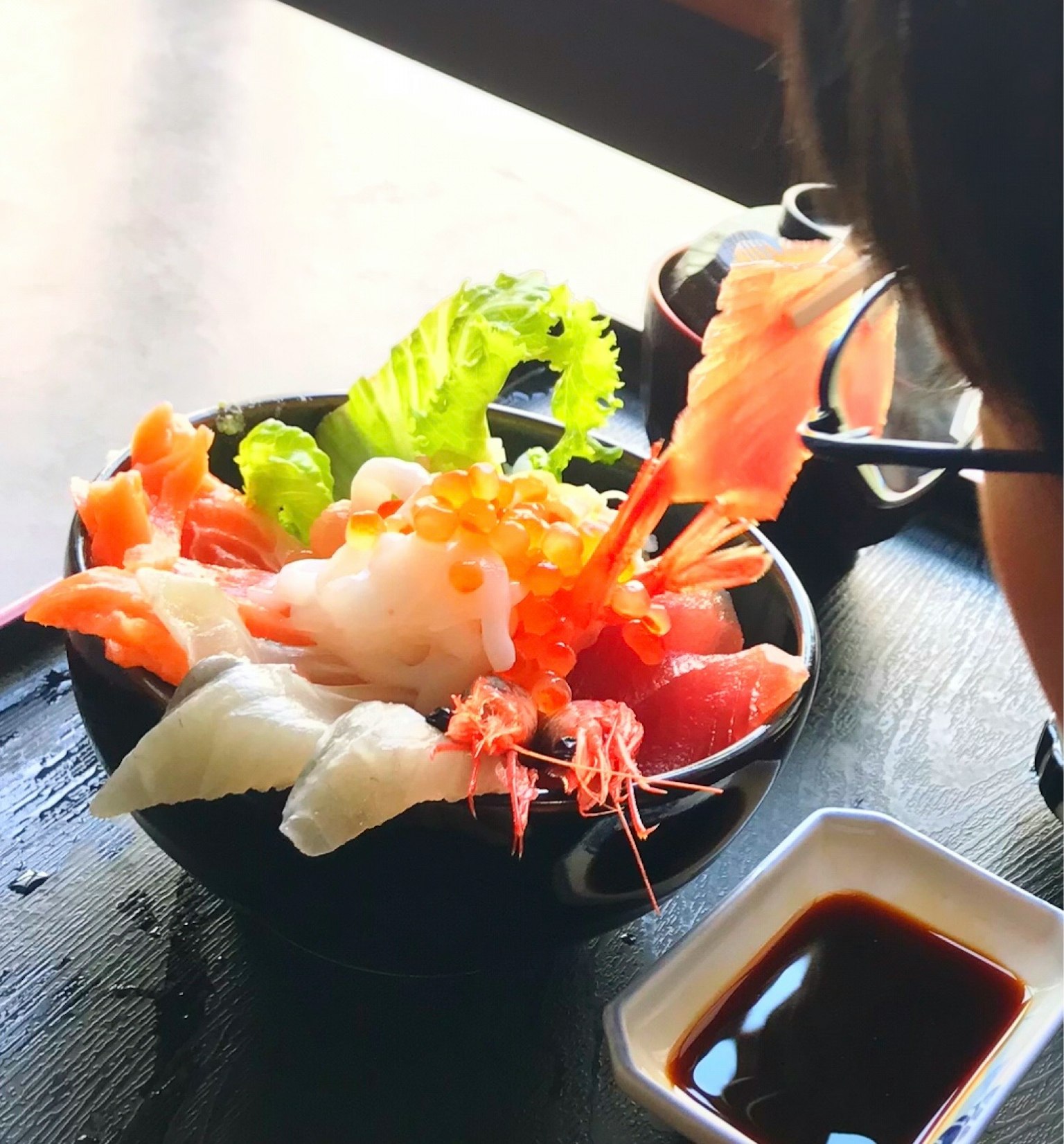 A bowl of fresh sashimi and shrimp garnished with lettuce