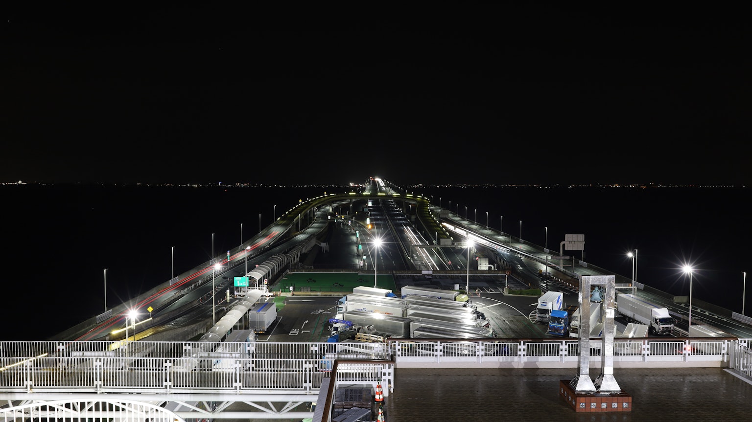 Escena de carretera iluminada y tráfico que conduce al mar por la noche