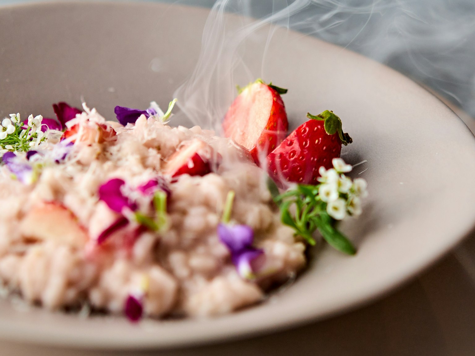 Creamy dessert with smoked strawberries and edible flowers