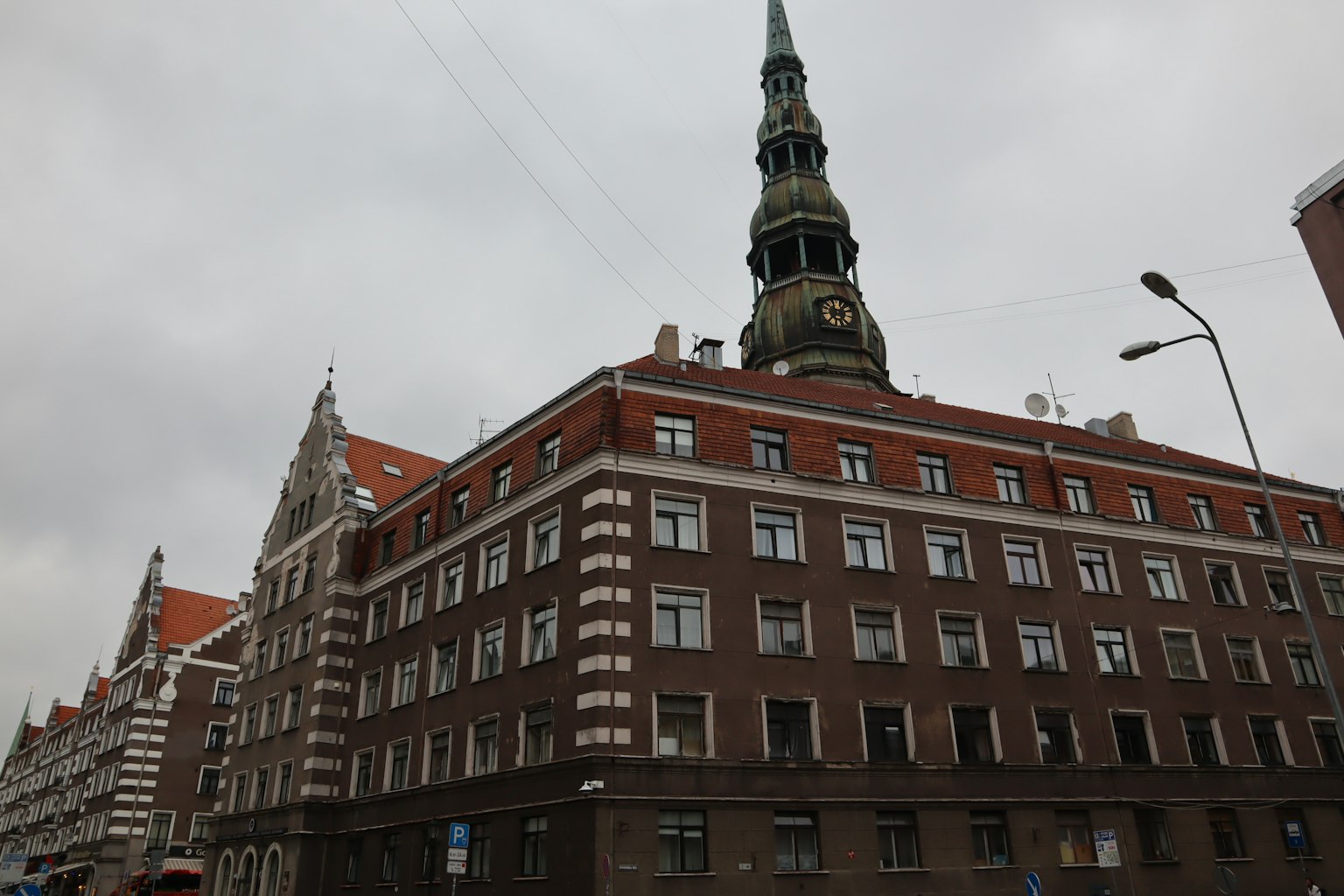 Exterior de un edificio histórico bajo un cielo gris con techos rojos y una aguja