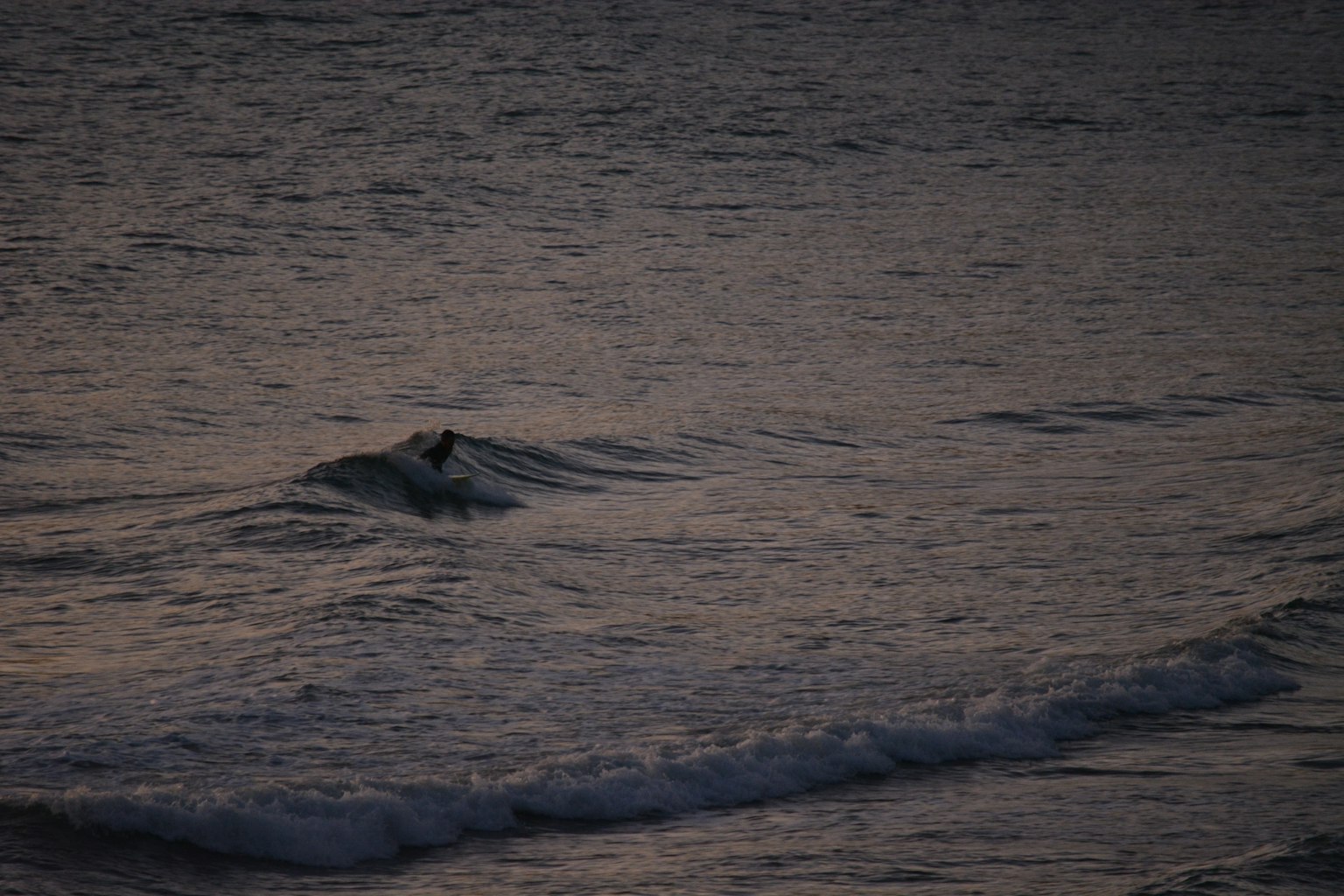 Dark ocean waves gently rolling in the evening light