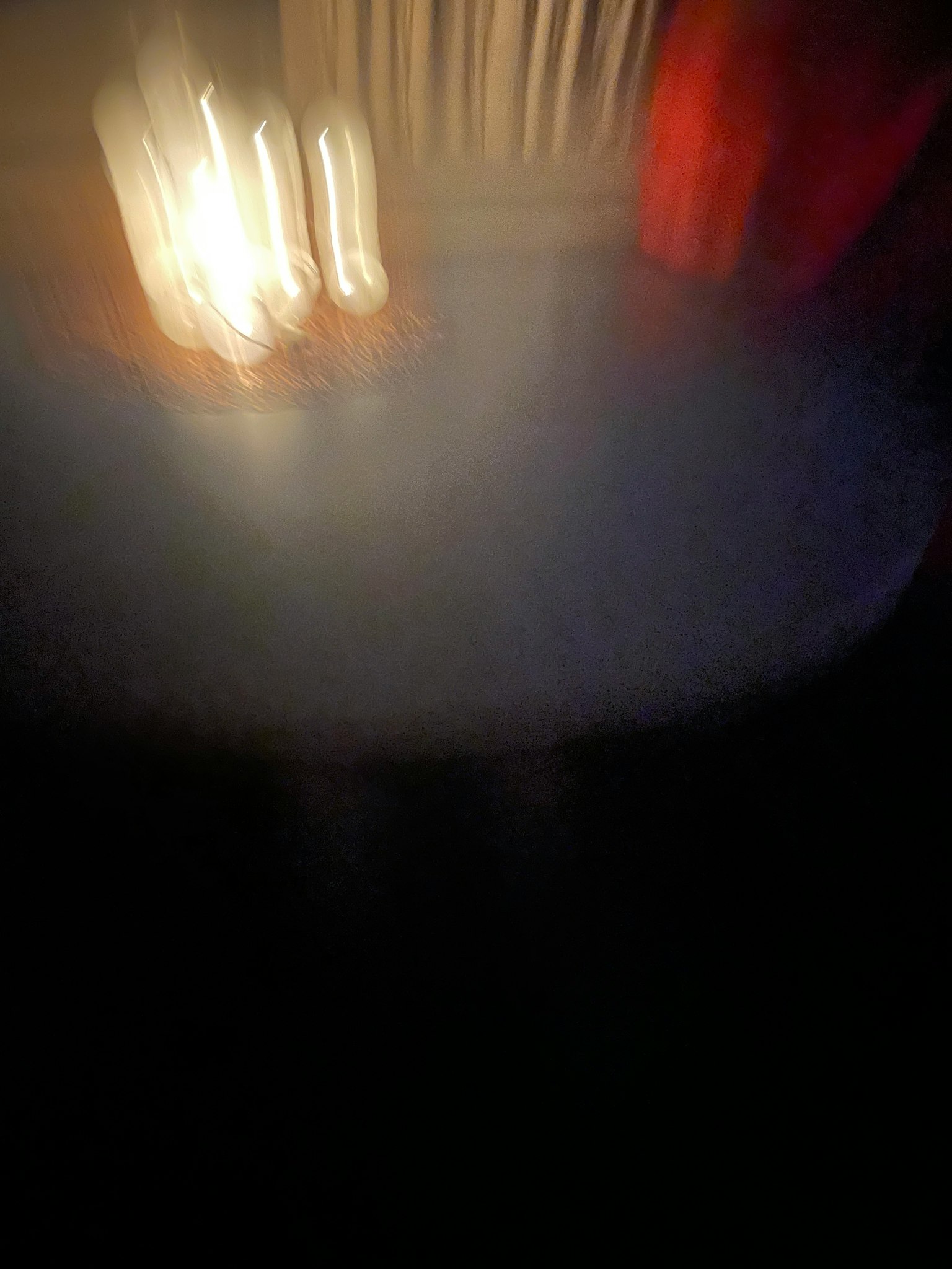 Verschwommene Darstellung eines Tisches mit flackerndem Kerzenlicht in einer dunklen Umgebung
