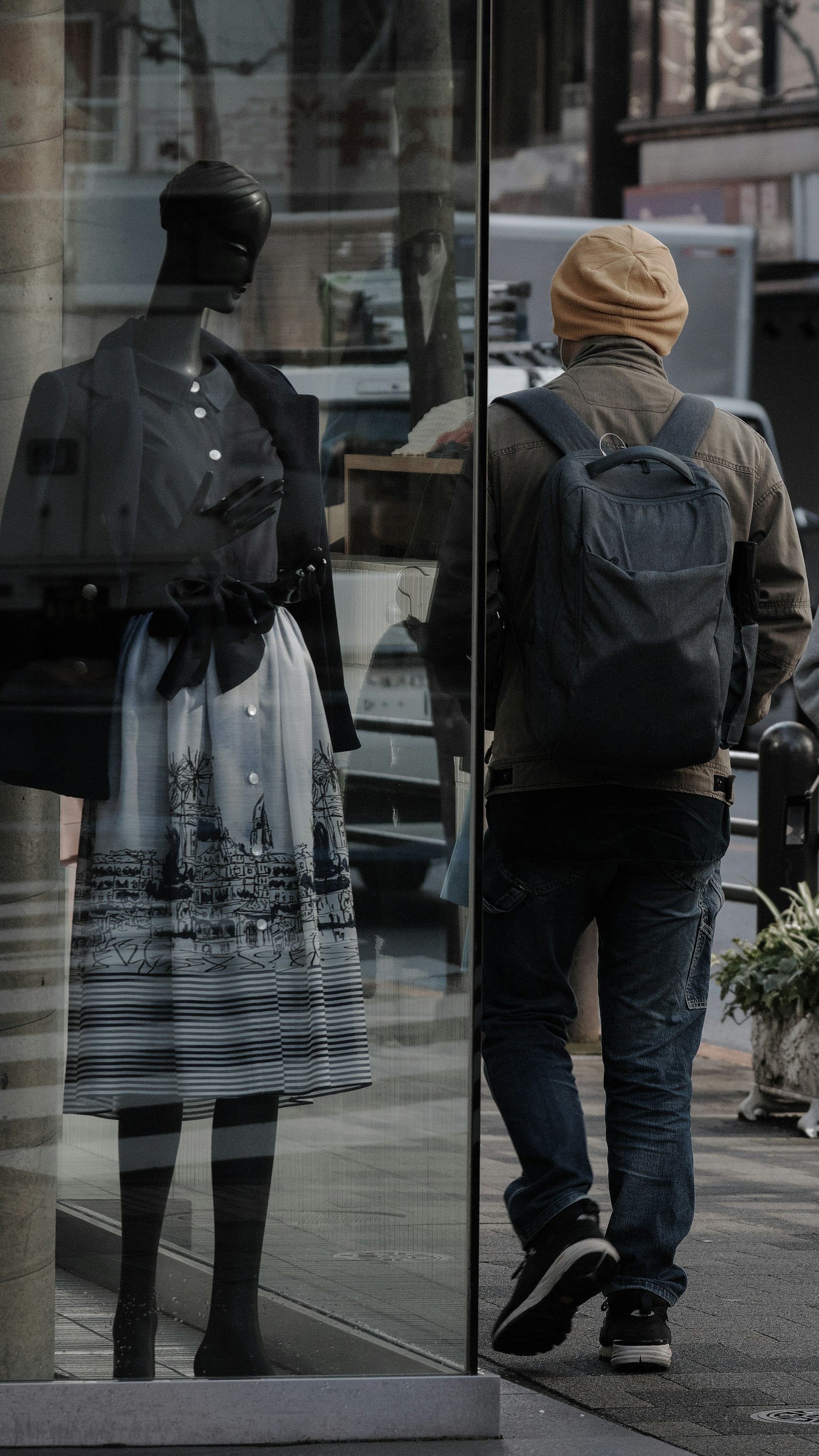 드레스를 입은 마네킹이 있는 상점을 지나가는 남자