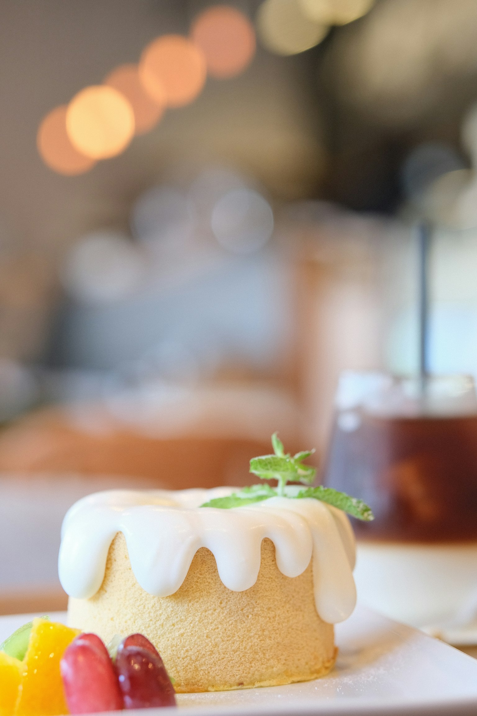 Pastel con glaseado blanco y una bandeja de frutas en una mesa de café