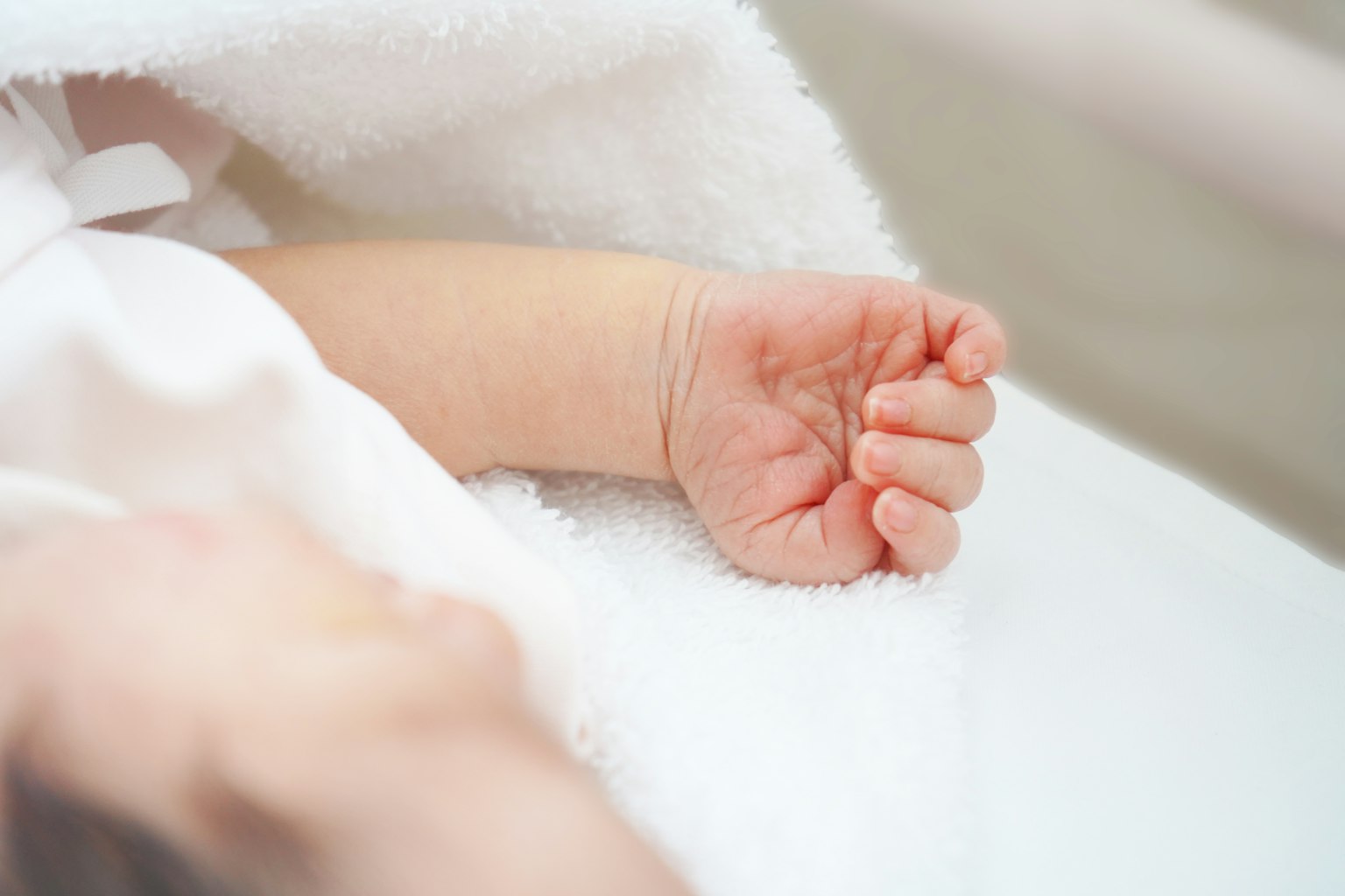 Primo piano della mano di un bambino avvolta in un morbido asciugamano bianco