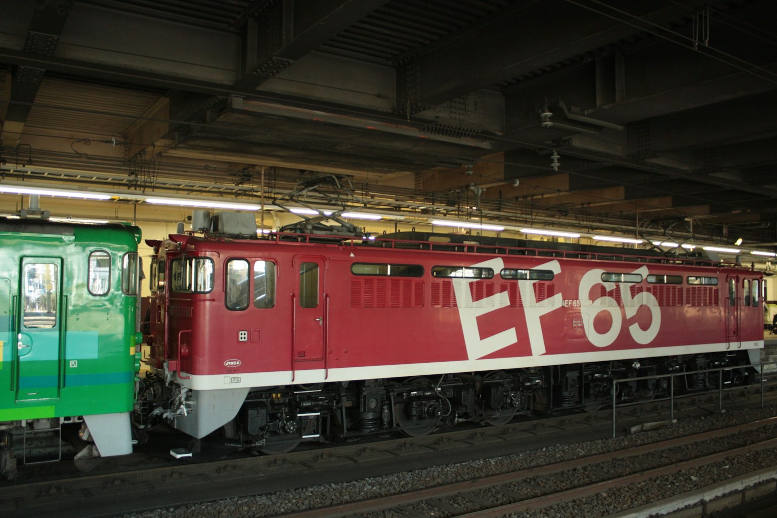 หัวรถจักร EF65 สีแดงจอดอยู่ที่ชานชาลาสถานี