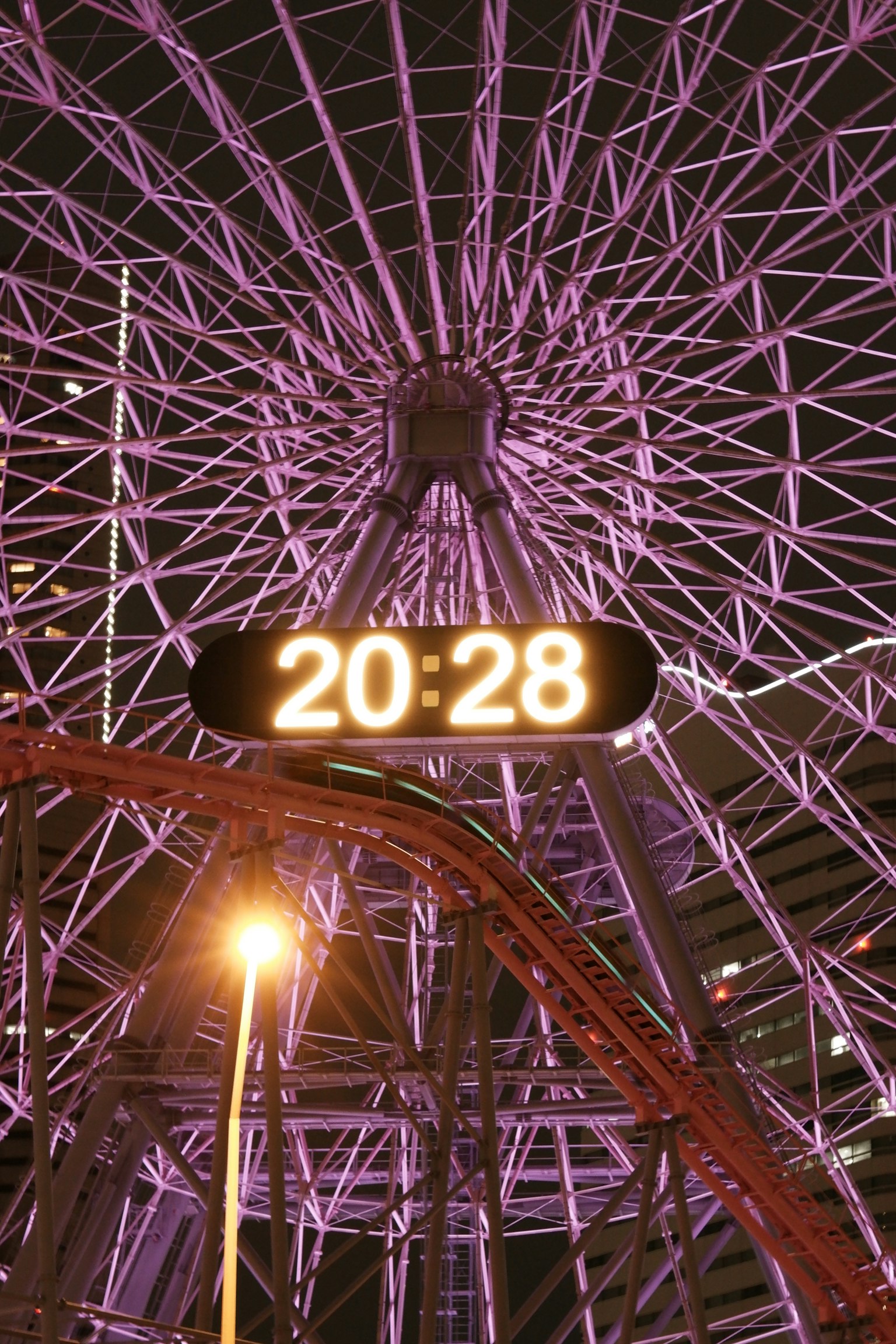 Night view of a purple Ferris wheel with digital clock display