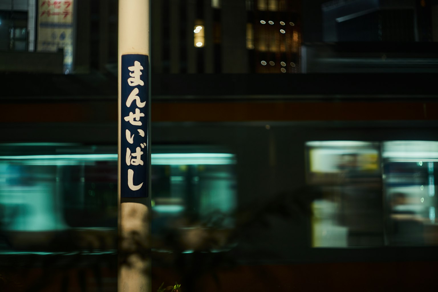 ฉากเมืองในเวลากลางคืนที่มีรถไฟที่เคลื่อนที่และป้ายสถานี