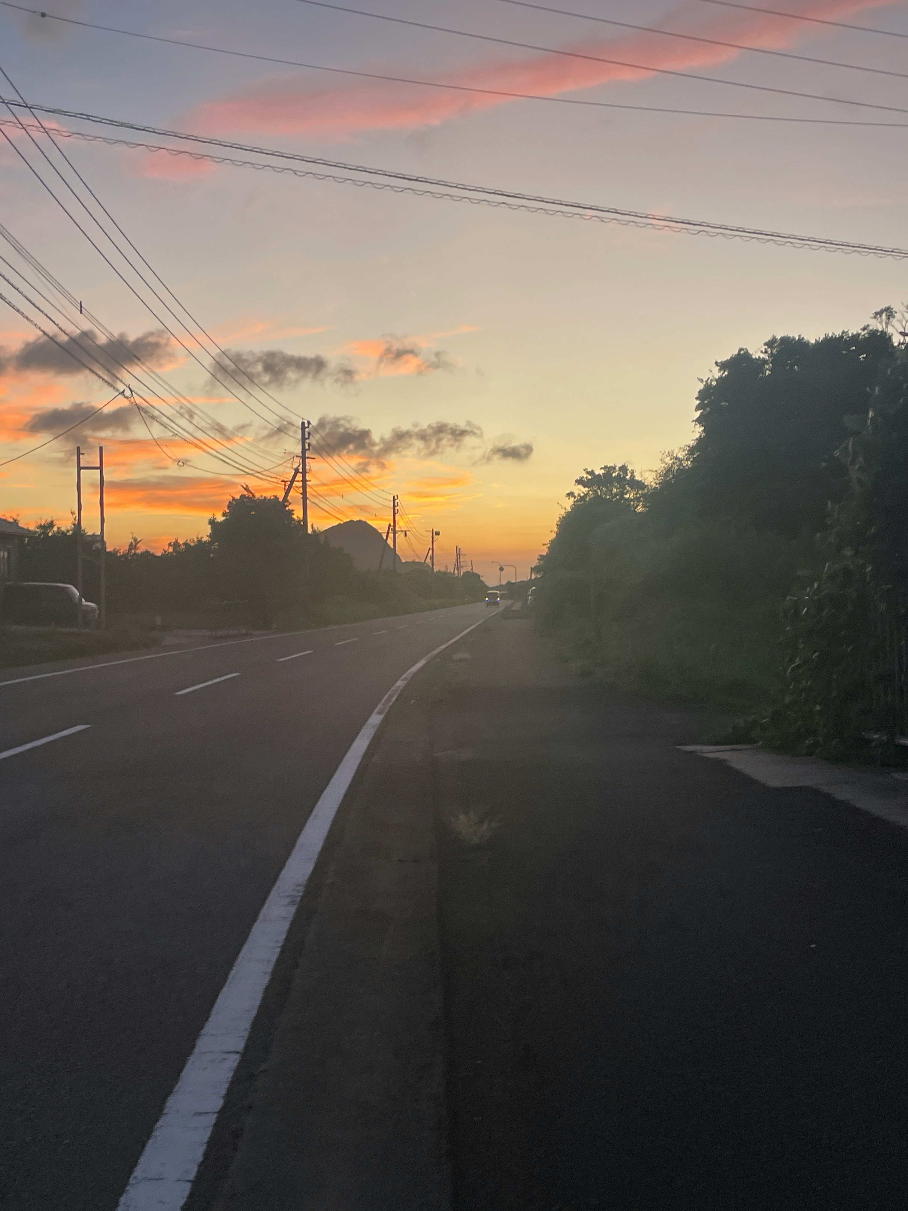 夕暮れの郊外道路を走る車線と電線のある風景