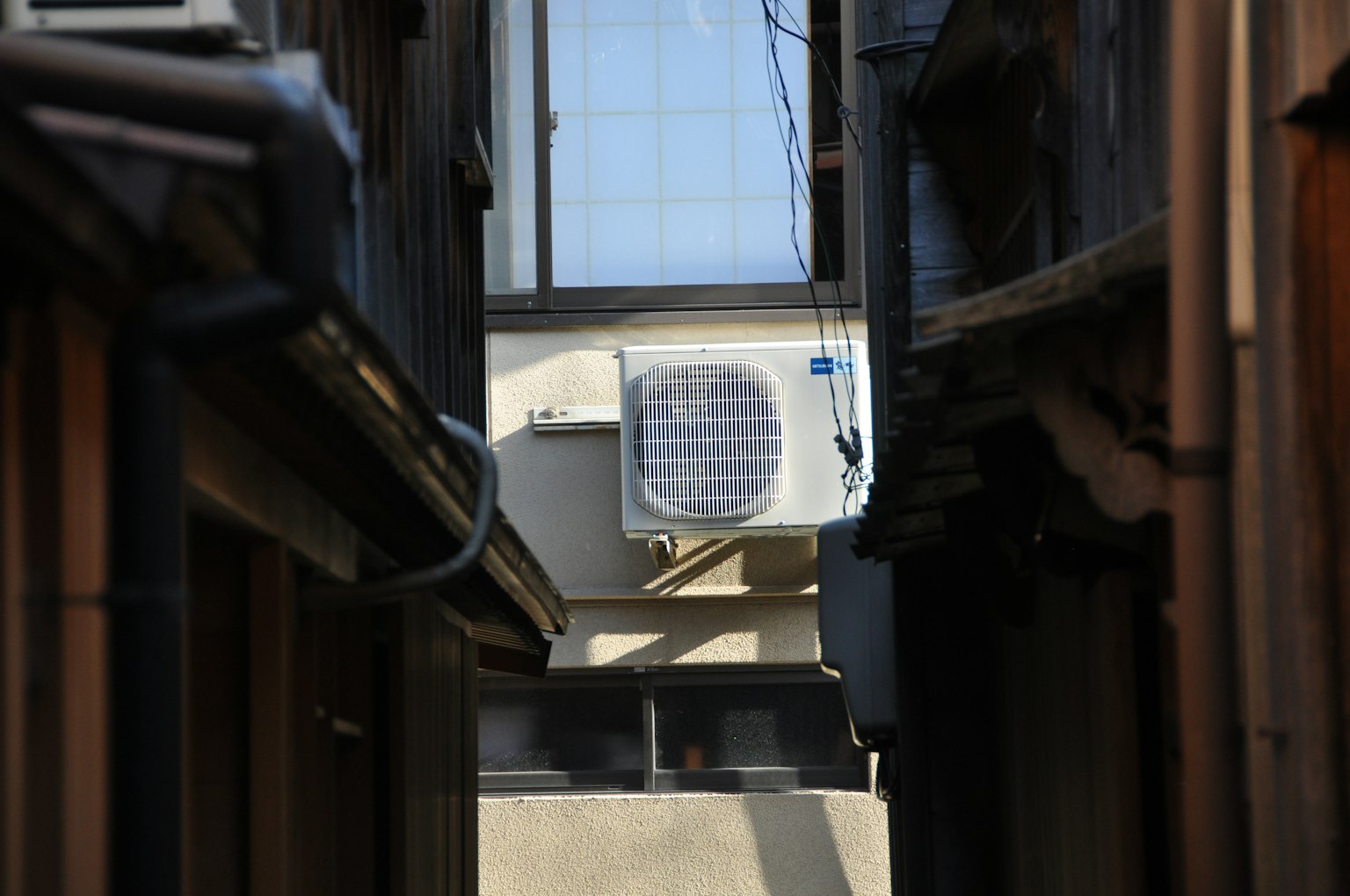 狭窄巷道中的空调机组，周围是木制建筑