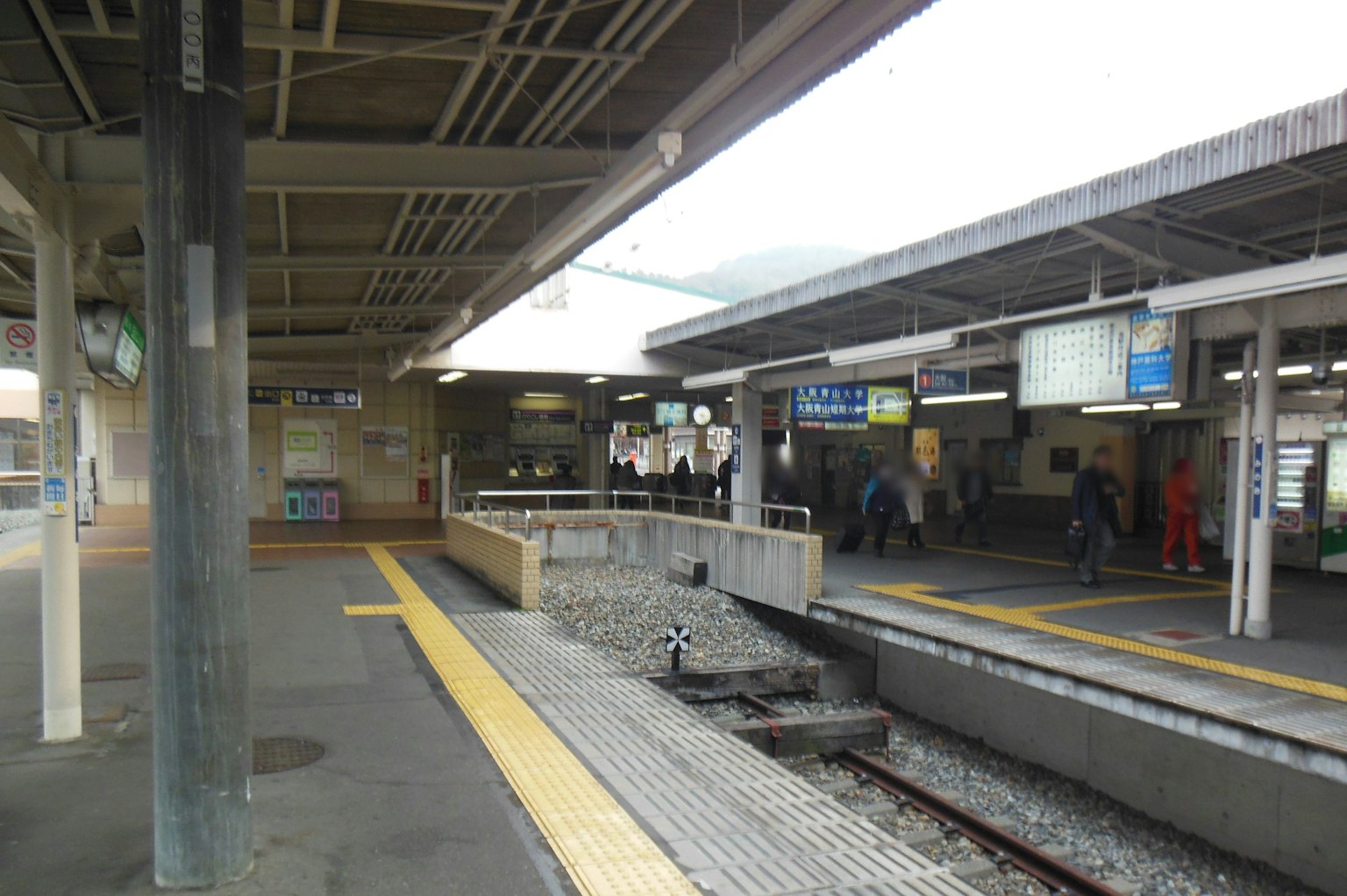 Pemandangan platform stasiun kereta dengan orang-orang dan papan tanda