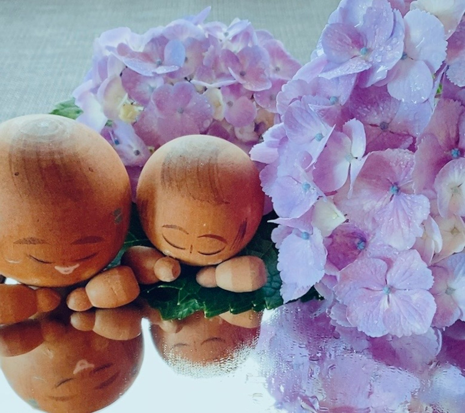 Dos pequeñas figuras de cerámica y flores moradas dispuestas en un entorno sereno