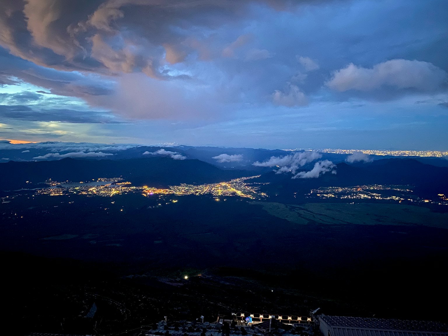 Vue nocturne d'une ville illuminée sous un ciel bleu et des nuages