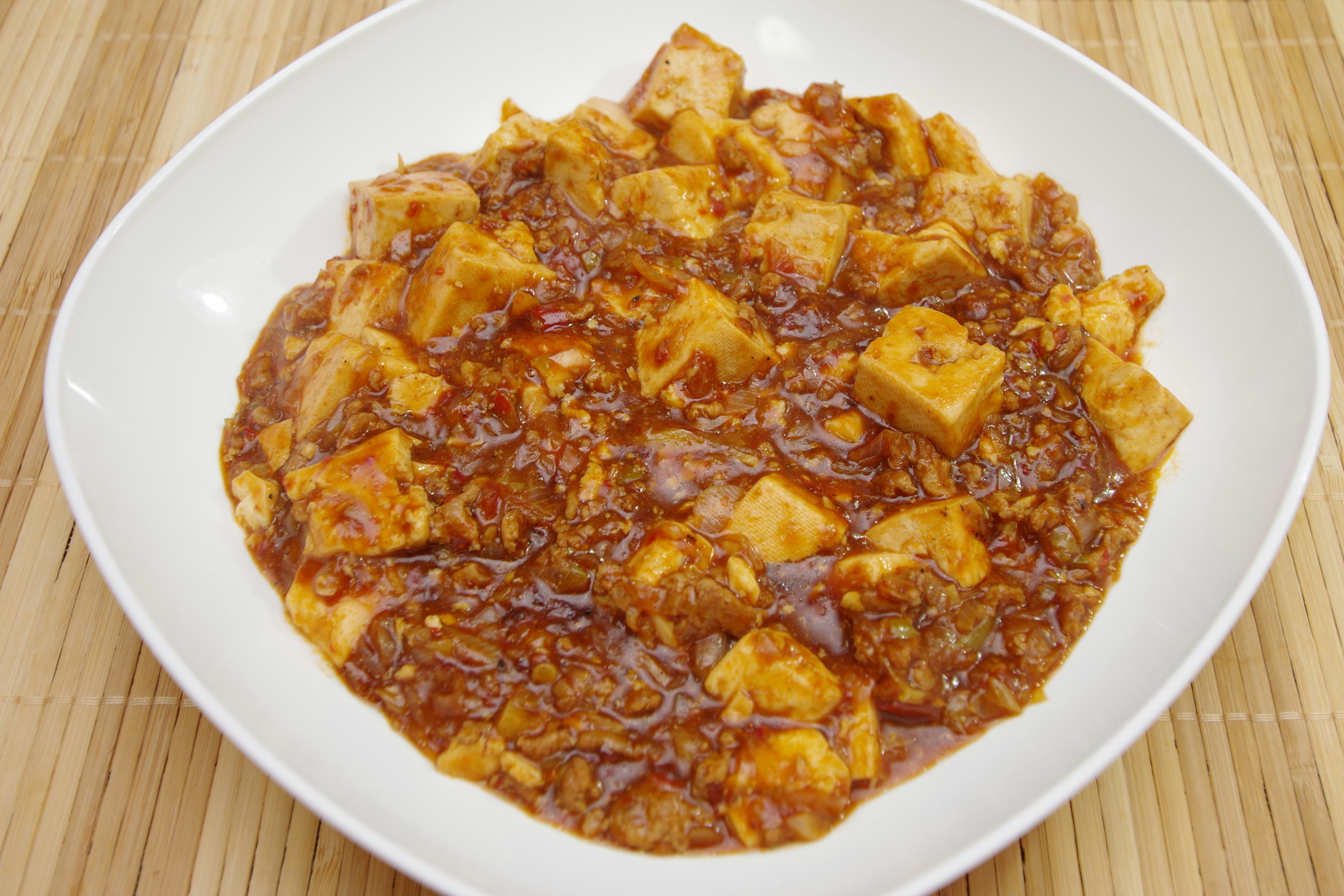 木目の上に盛られた麻婆豆腐のような辛味煮込み