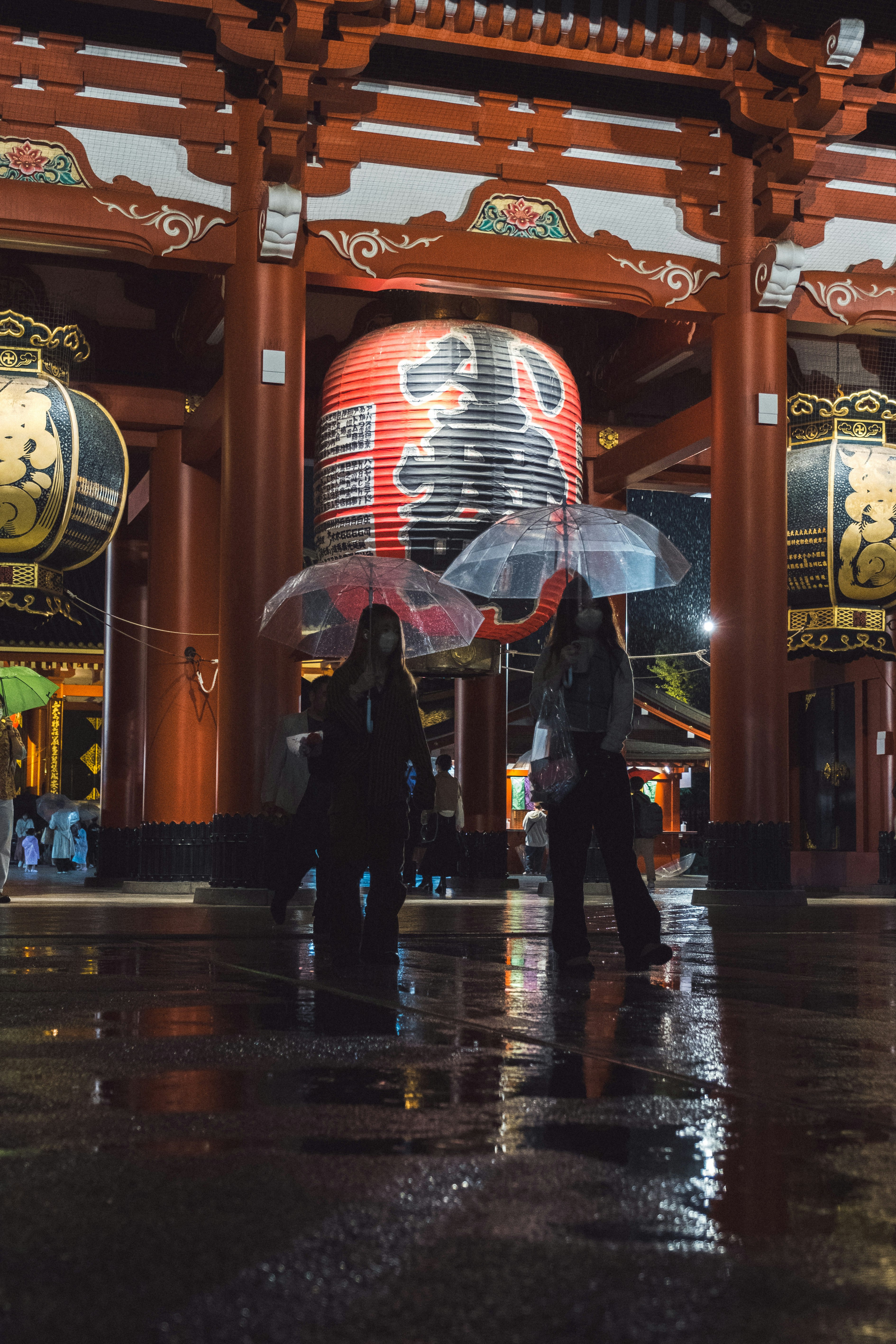 雨の神社の大きな提灯と参道の人影