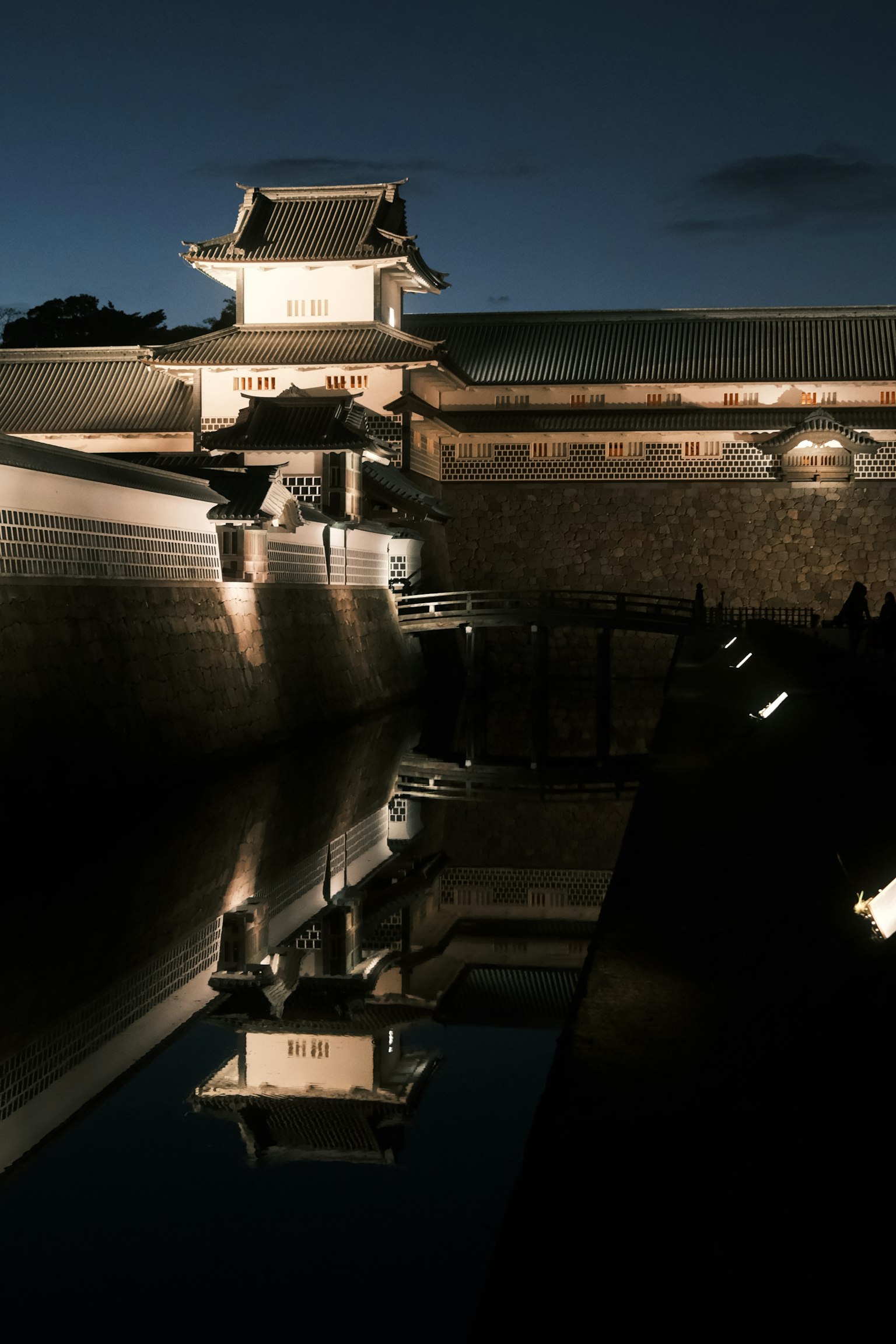 Schöne Aussicht auf die Schlossmauern und die Reflexionen der Gebäude im Wasser bei Nacht