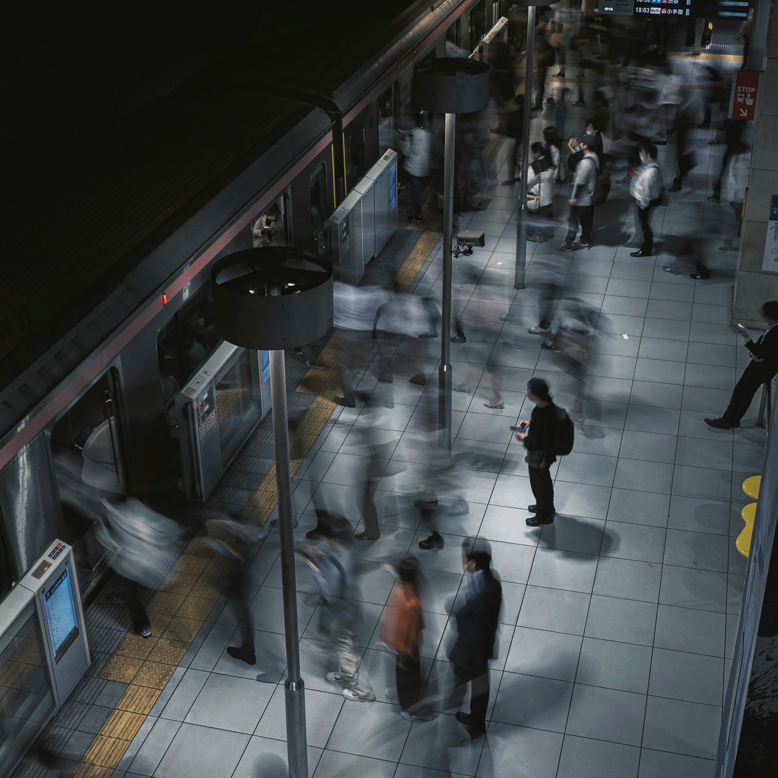 Piattaforma di stazione affollata con persone in movimento