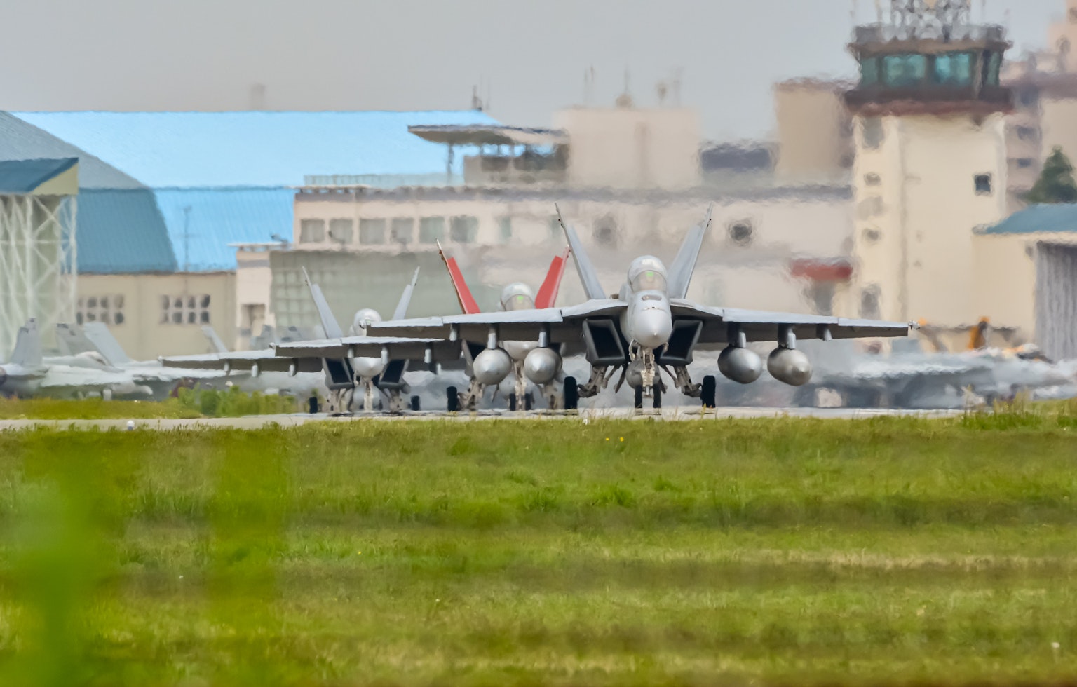 Militärflugplatz mit aufgereihten Kampfjets und Gebäuden im Hintergrund