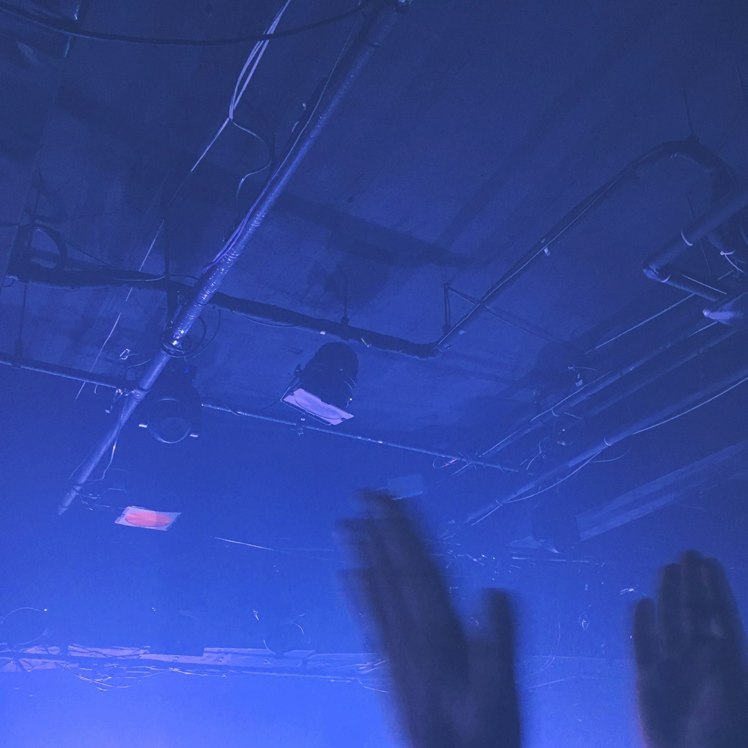 Silhouette di mani alzate sotto un'illuminazione blu