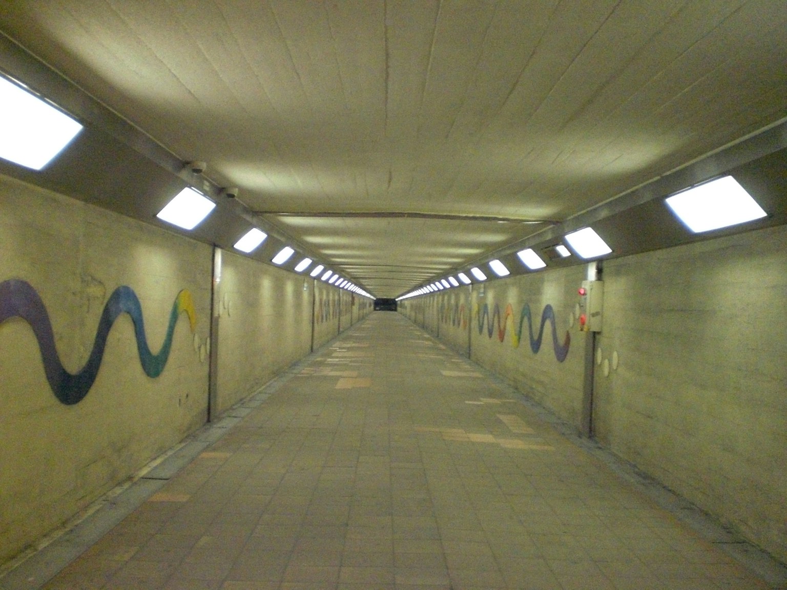 Largo túnel con iluminación brillante y arte mural