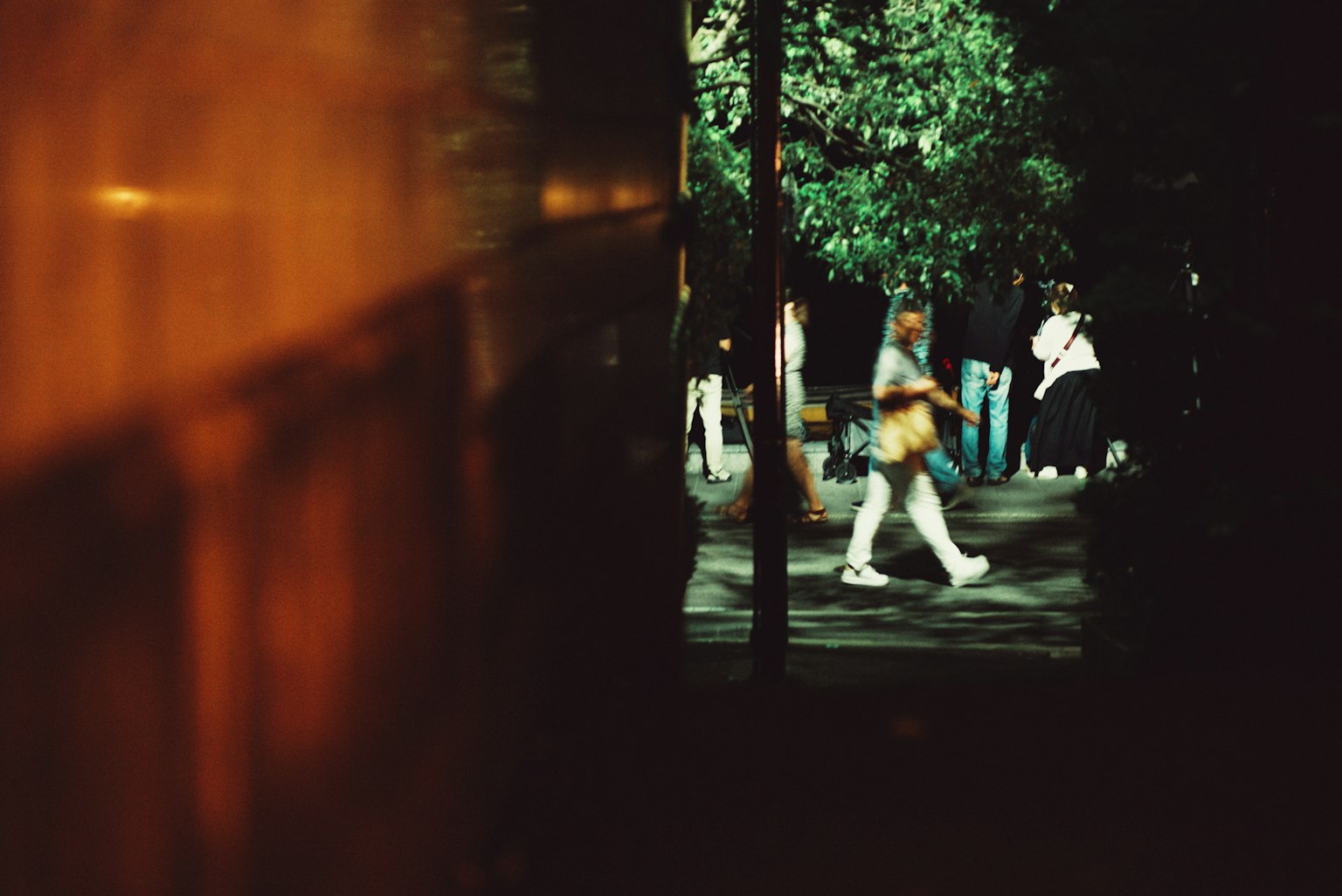 Des gens se rassemblent dans une rue faiblement éclairée avec des arbres verts en arrière-plan