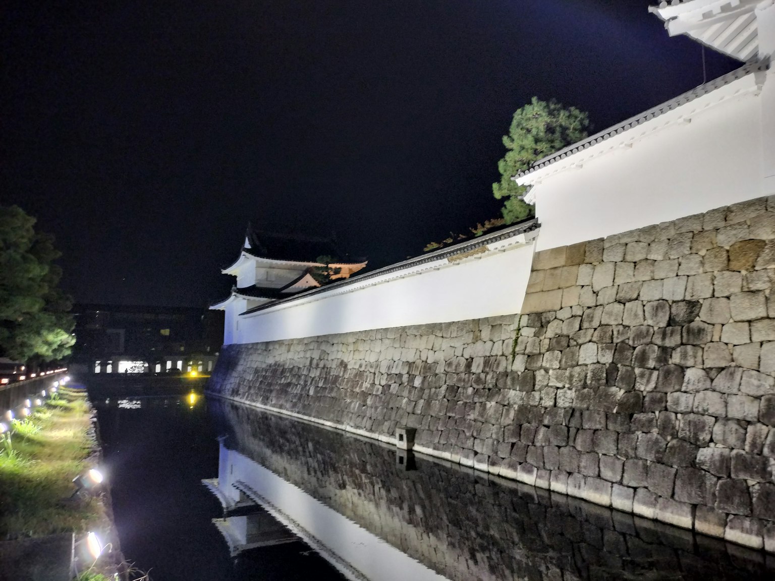 Vue nocturne d'un mur de château avec des reflets dans l'eau