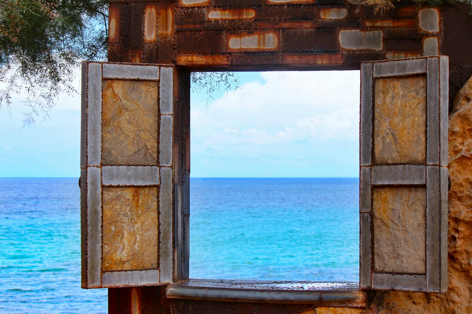 Antico telaio di finestra che si affaccia su un mare blu