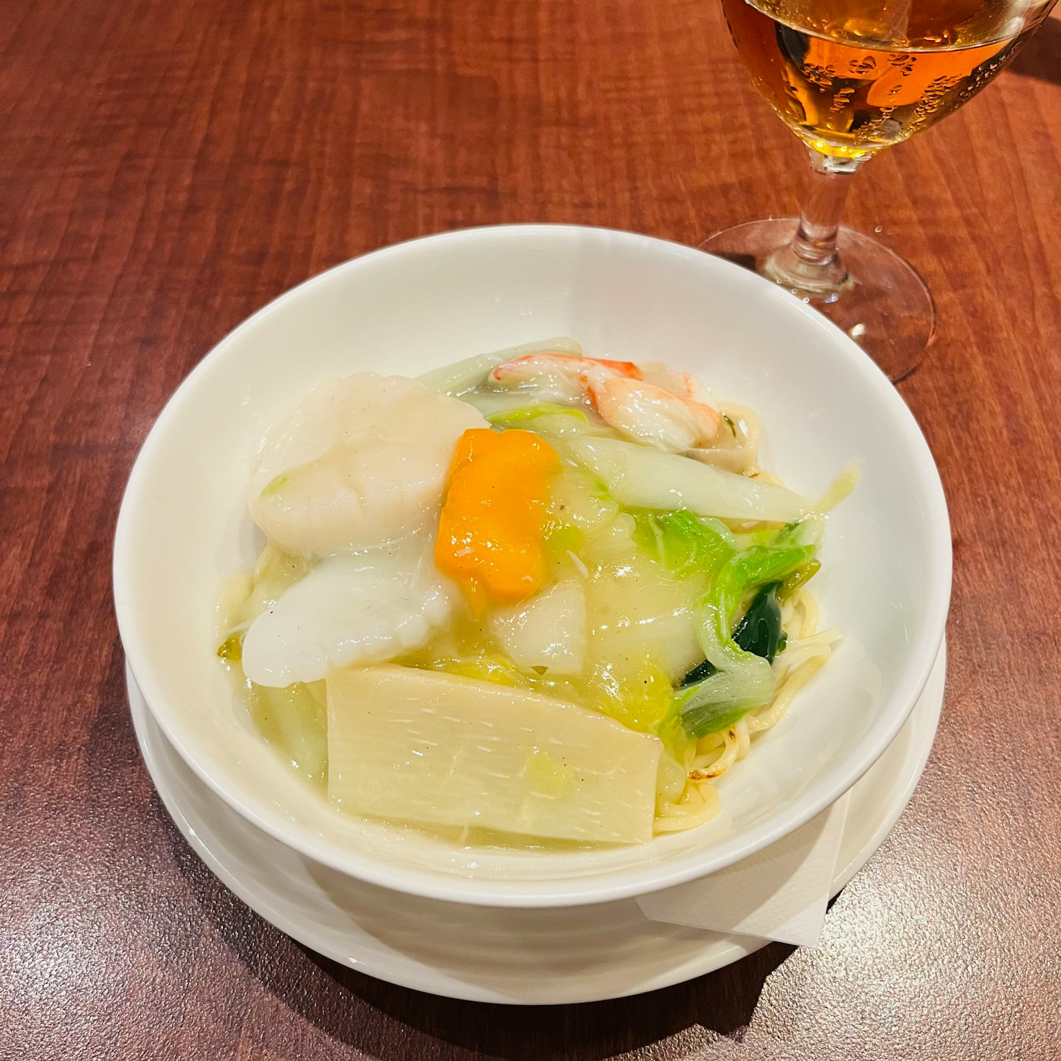 Eine weiße Schüssel mit Meeresfrüchte- und Gemüsesuppe, garniert mit Eigelb