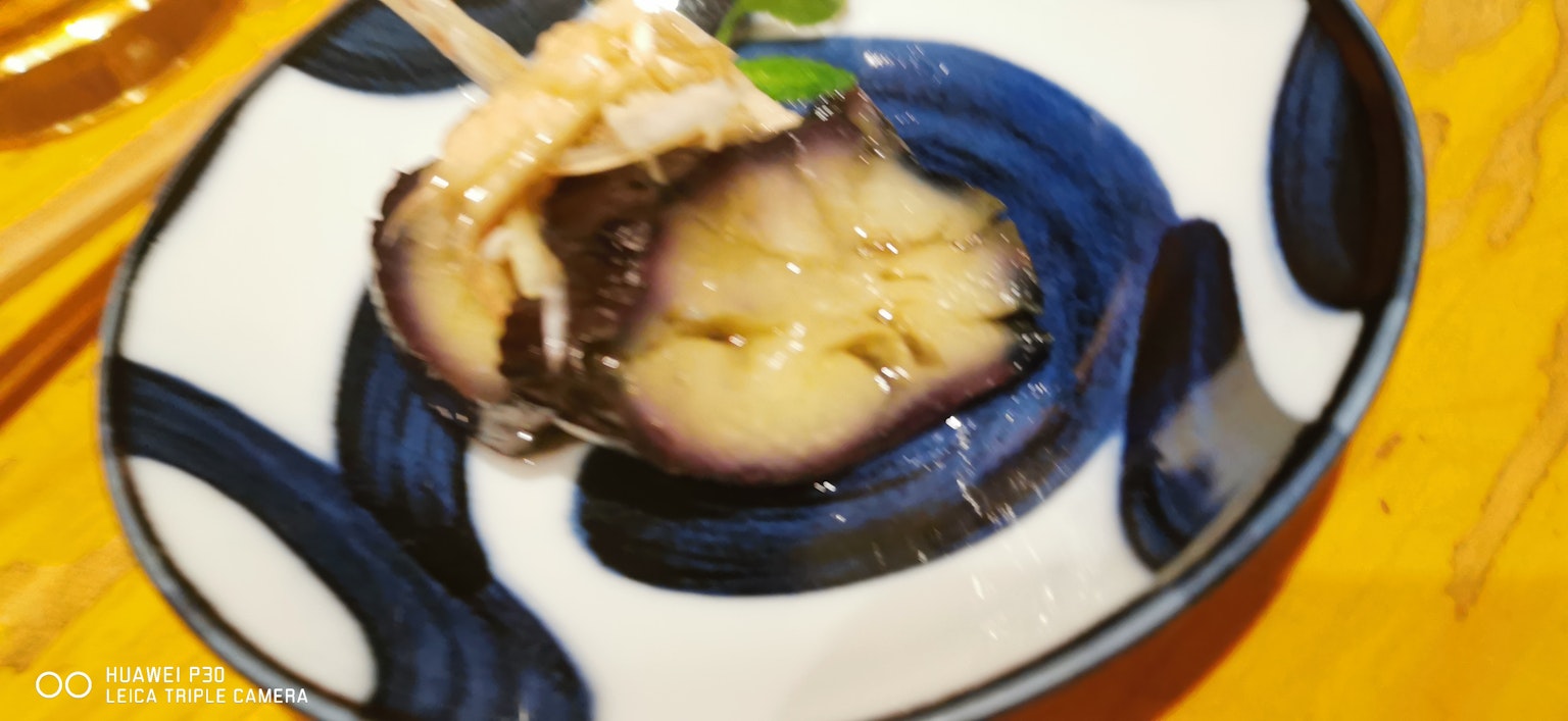 Plato de berenjena con aderezo servido en un plato de diseño azul
