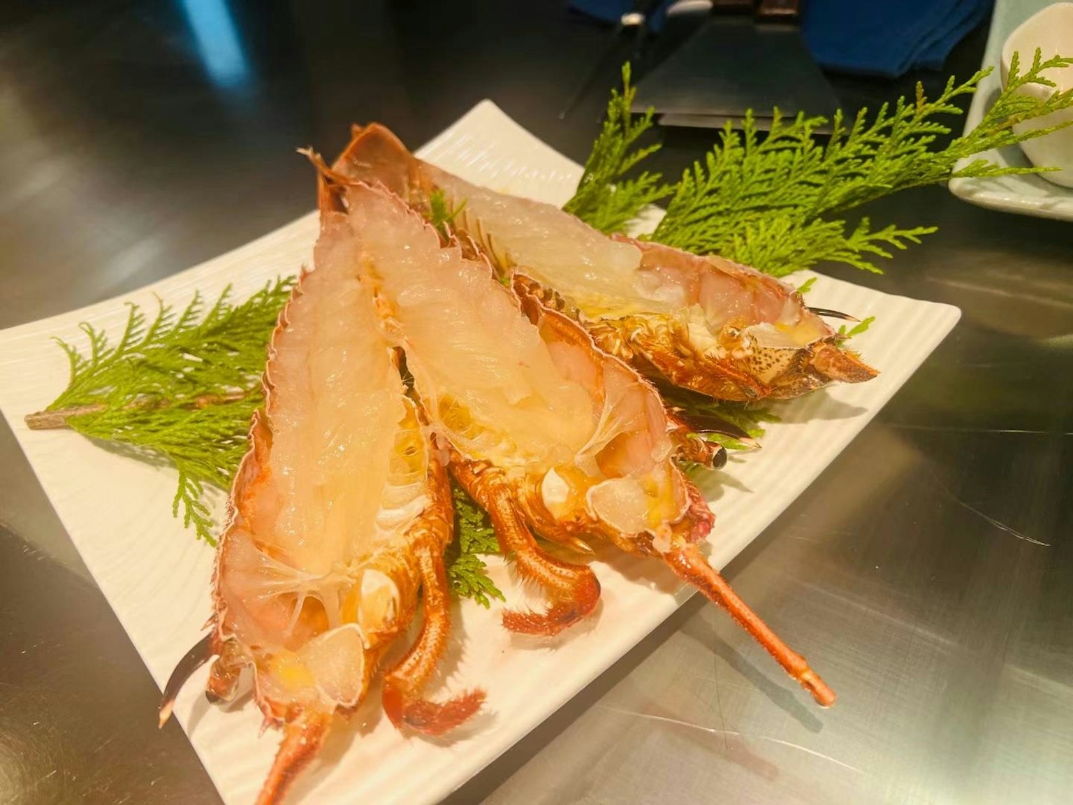 จานซาชิมิของกุ้งสดที่ตกแต่งด้วยใบเขียว