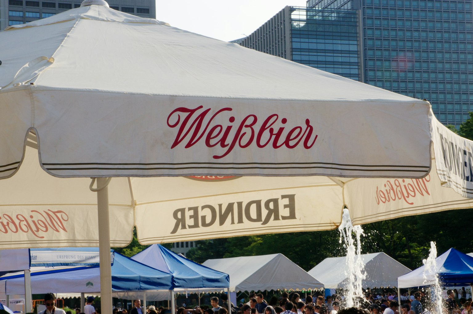 เต็นท์เบียร์กลางแจ้งที่มีป้าย Weißbier และฝูงชน