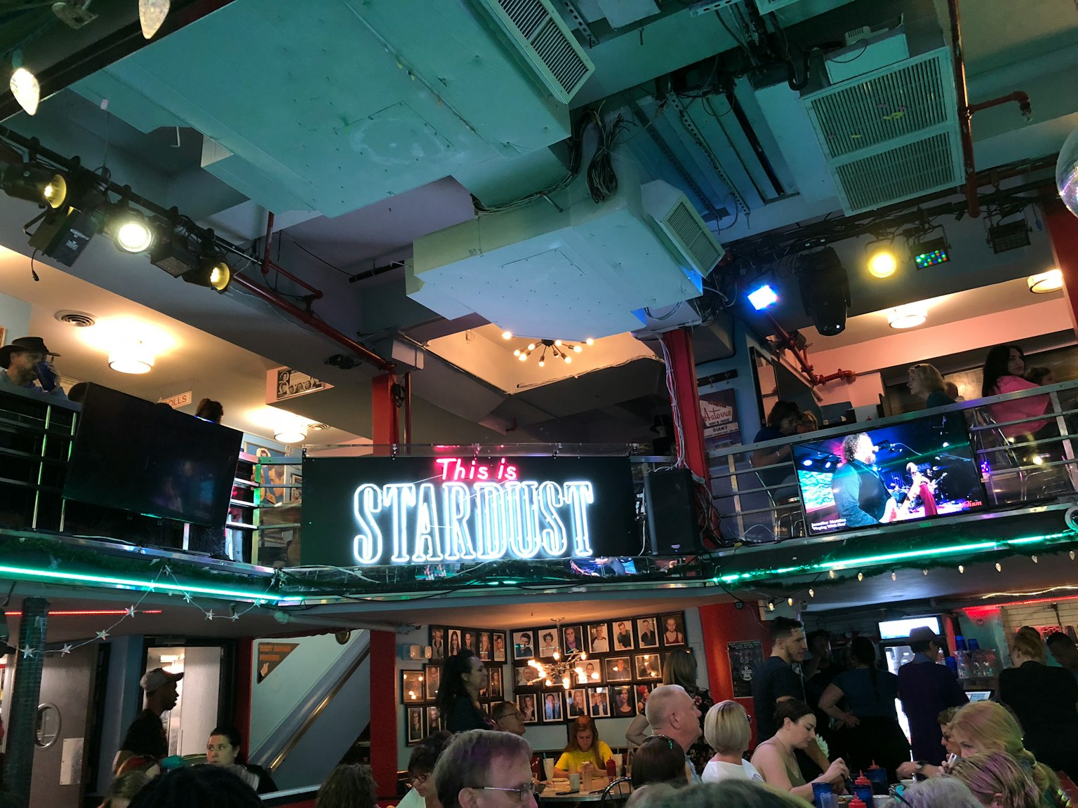 Interior of a lively restaurant featuring a Stardust sign with people enjoying music