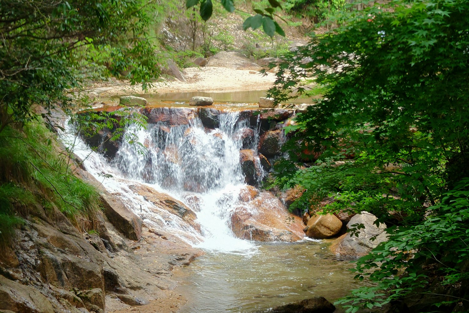 น้ำตกที่สวยงามล้อมรอบด้วยพืชพรรณเขียวชอุ่มน้ำไหลผ่านก้อนหิน
