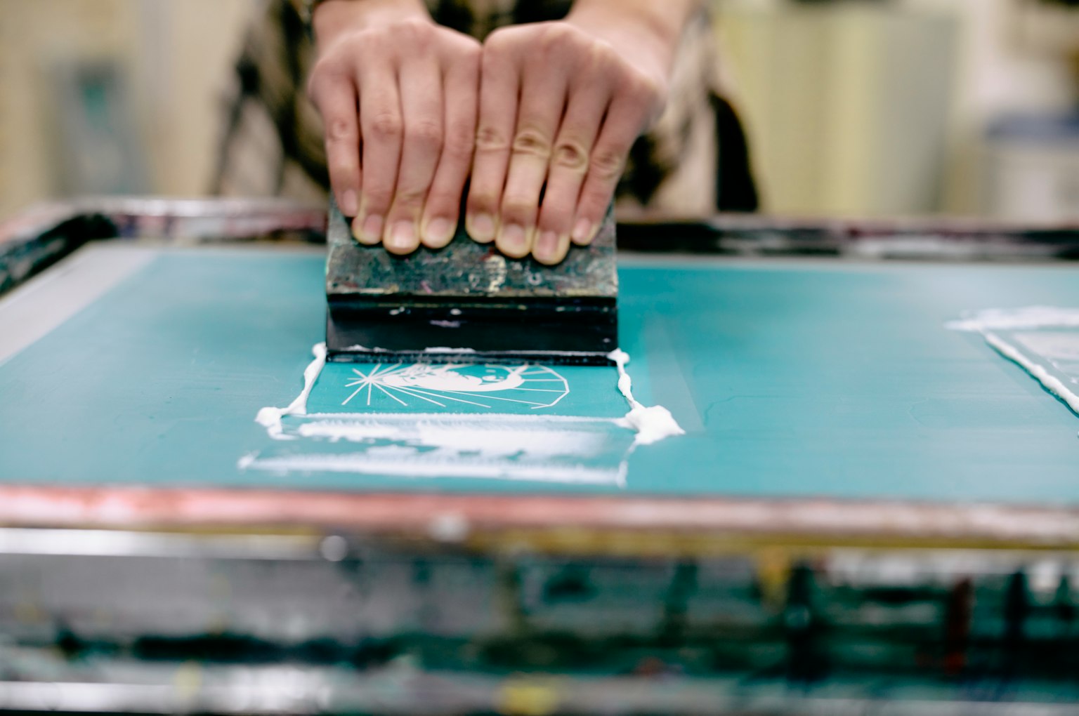 Hands using a squeegee in a screen printing process