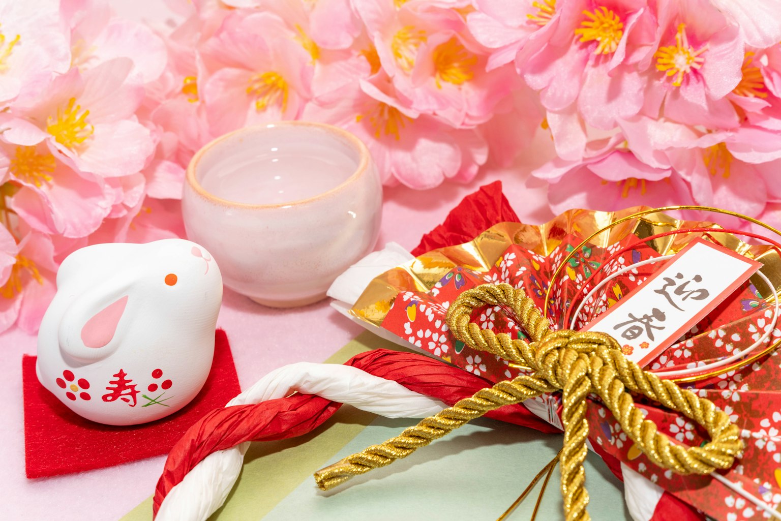 Colorful arrangement featuring a white rabbit figurine and festive decorations against a backdrop of cherry blossoms