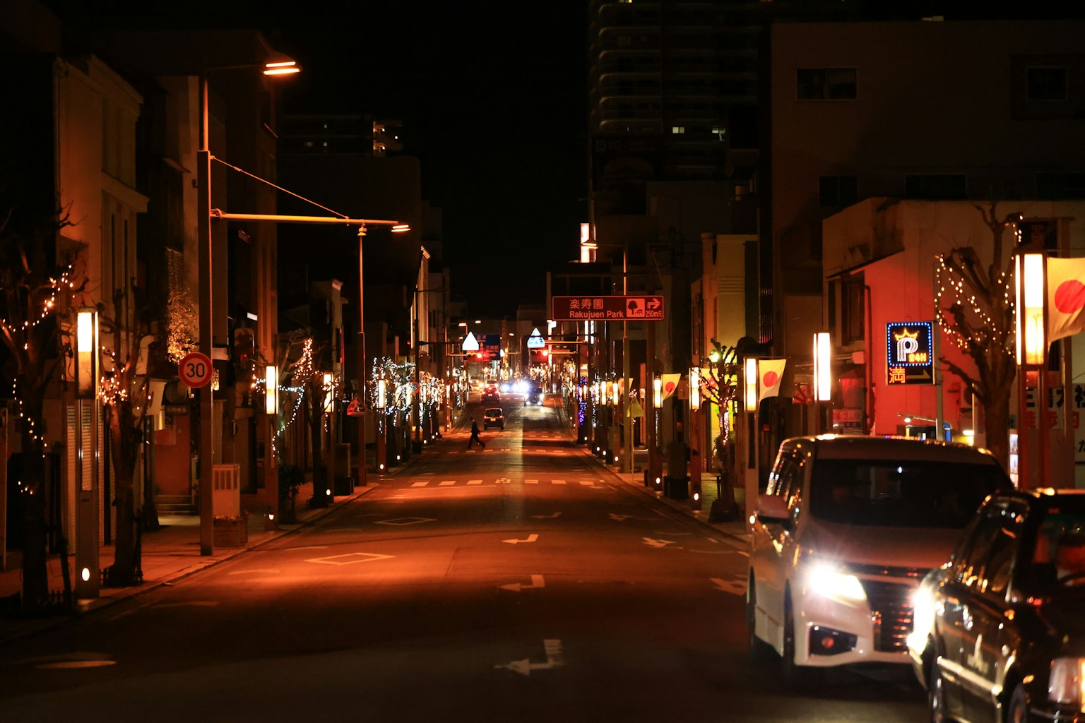 Una calle de noche bordeada de luces y coches estacionados