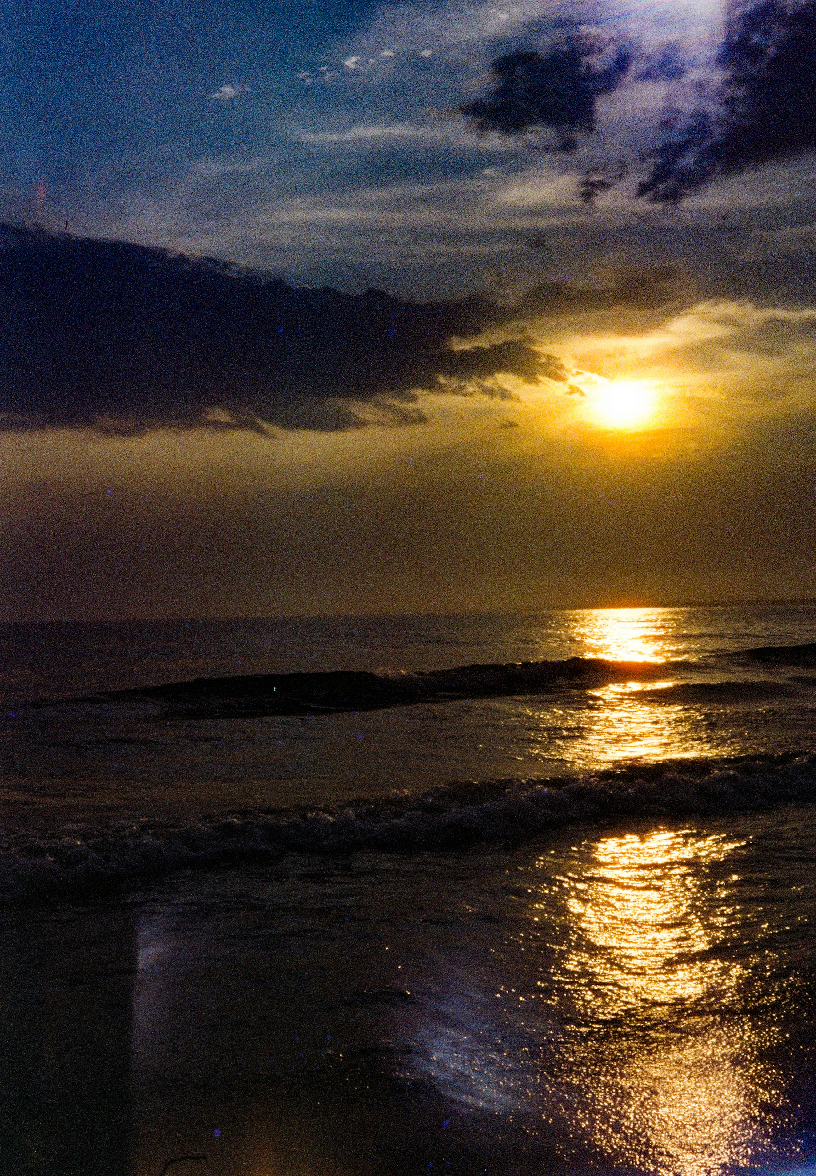 夕日に照らされる海辺の波と雲の空