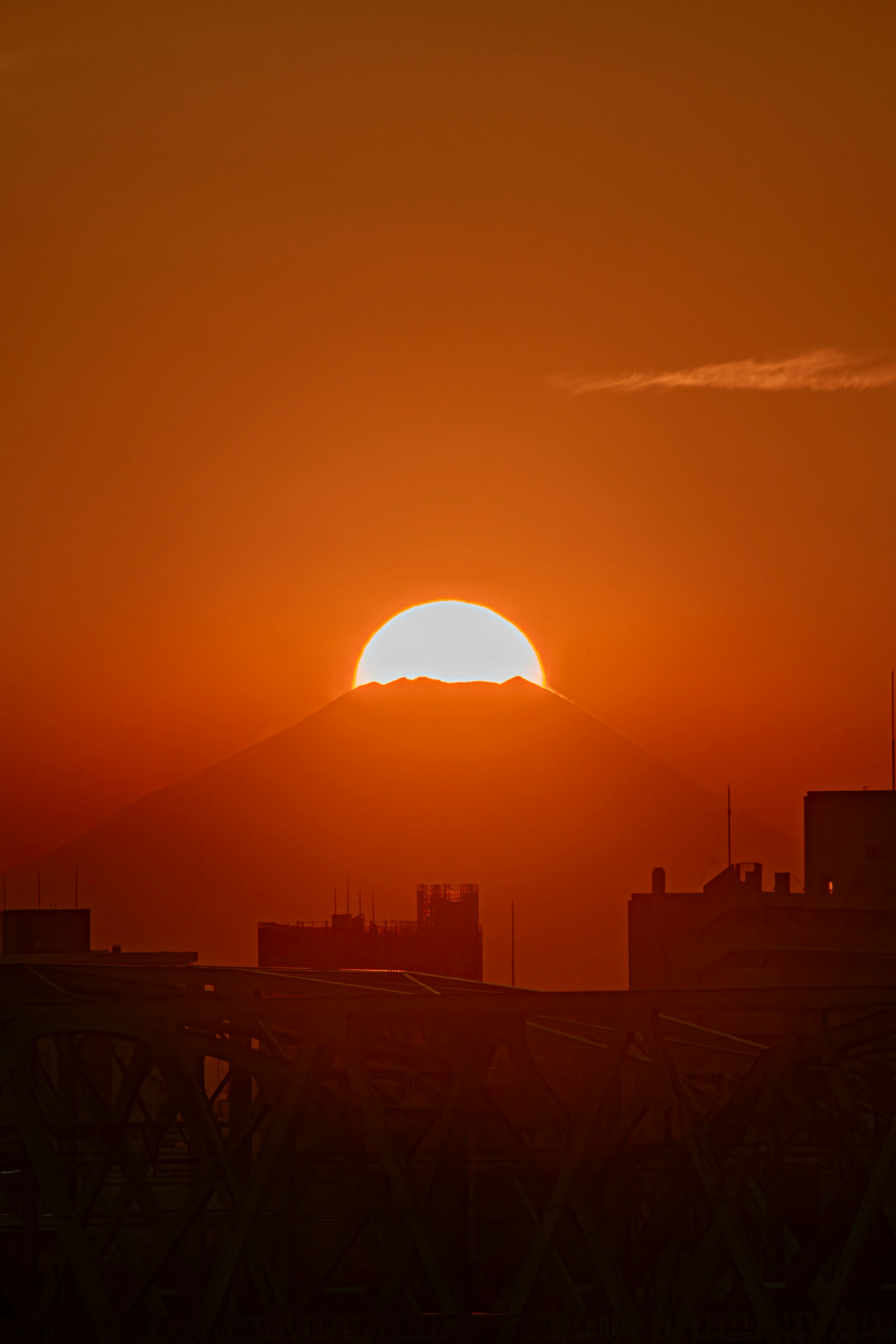 Sole « diamante » tipo Fuji sopra lo skyline cittadino al tramonto